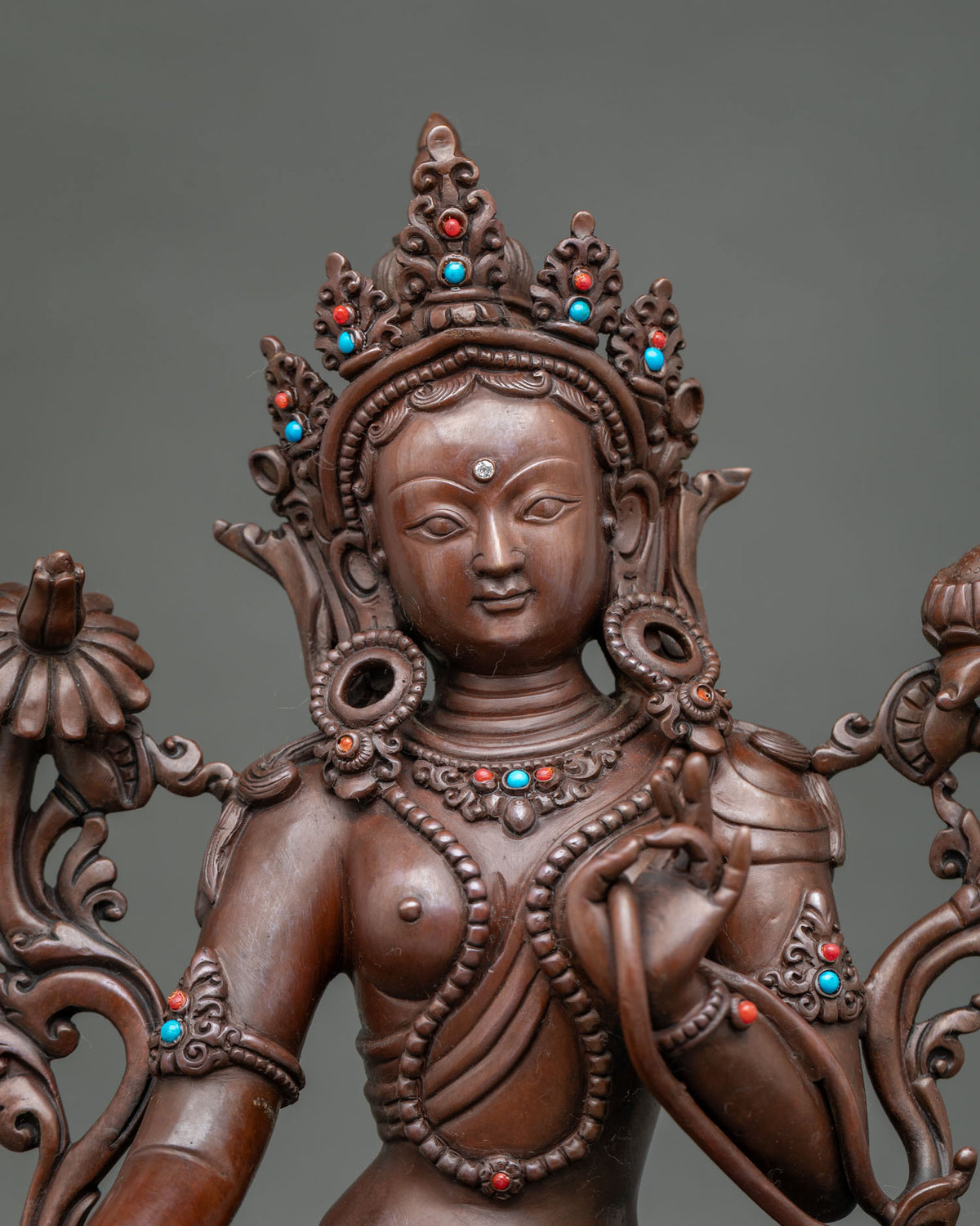 Close-up of Tibetan Green Tara statue face and crown with turquoise and coral stones