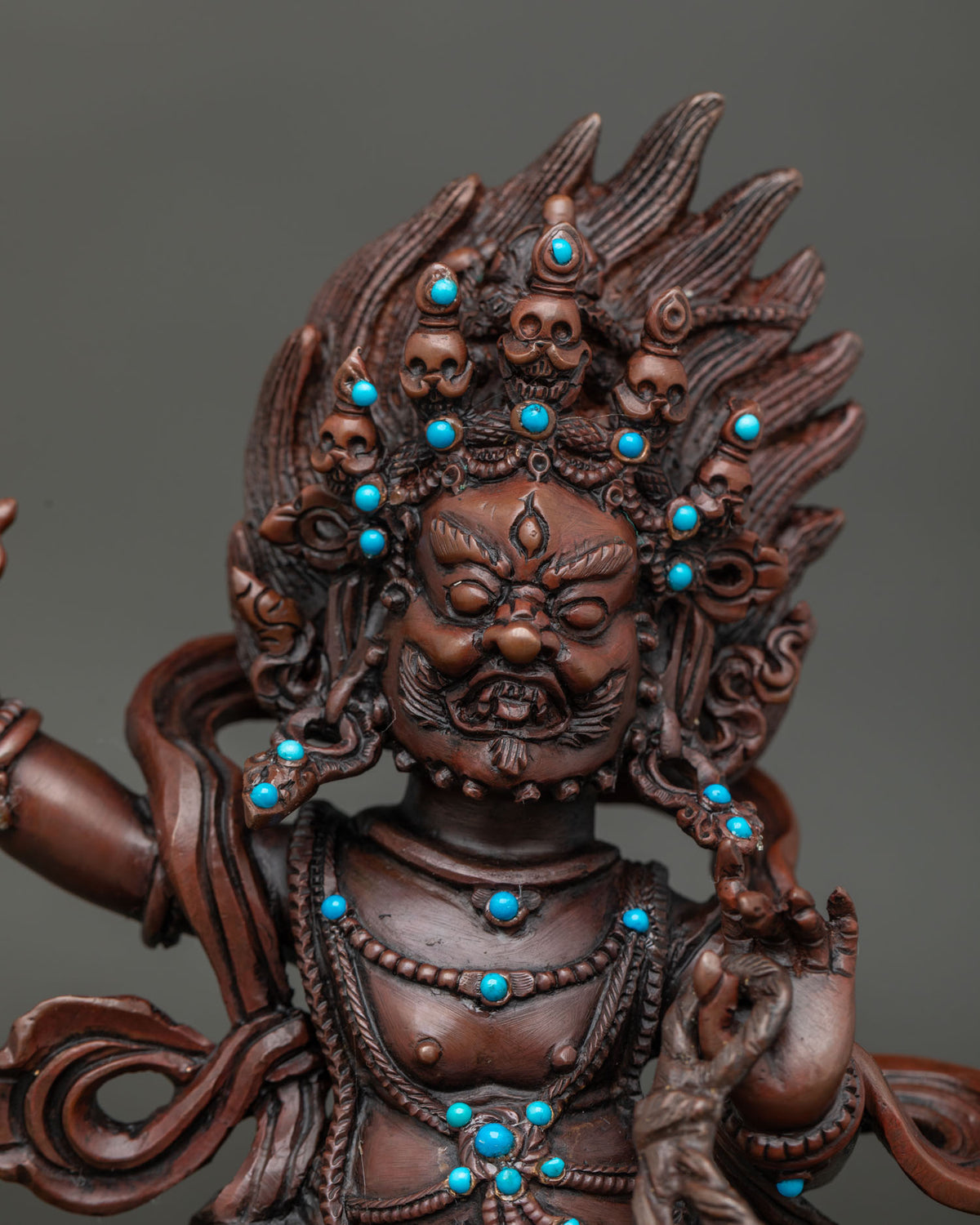 Close up of Vajrapani fierce expression skull crown and oxidized copper details.