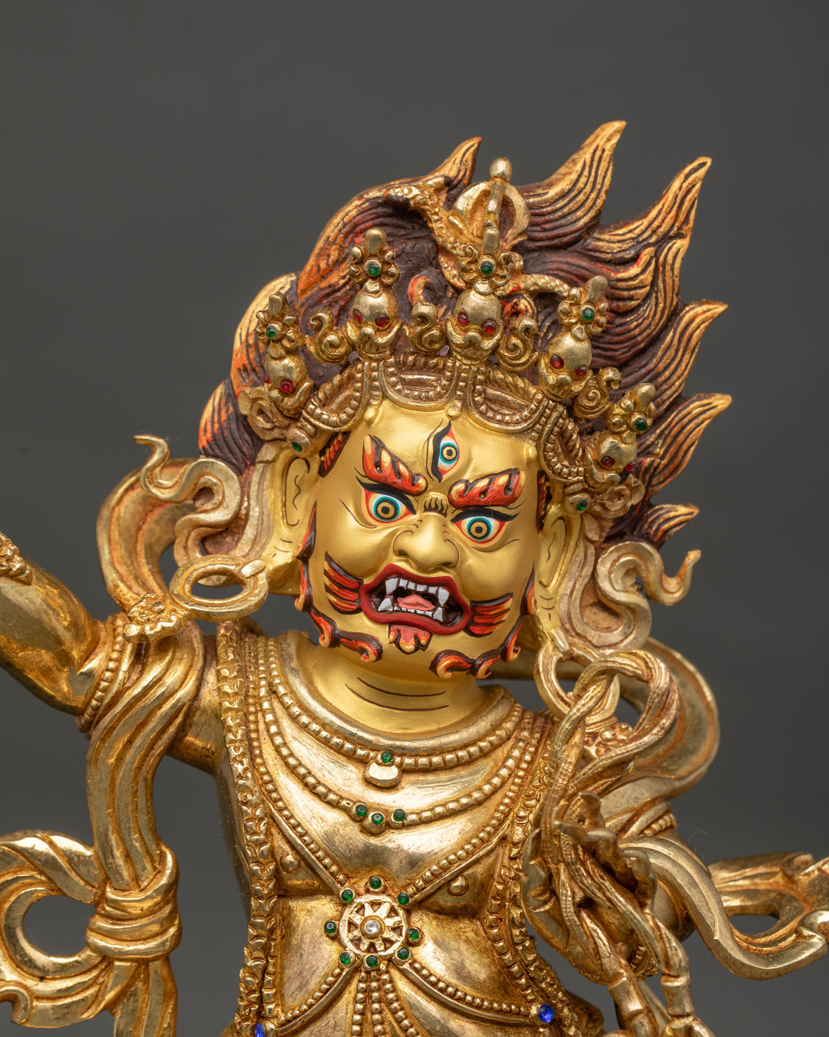Close up of vajrapani wrathful expression tiger skin garment and gold gilded details.