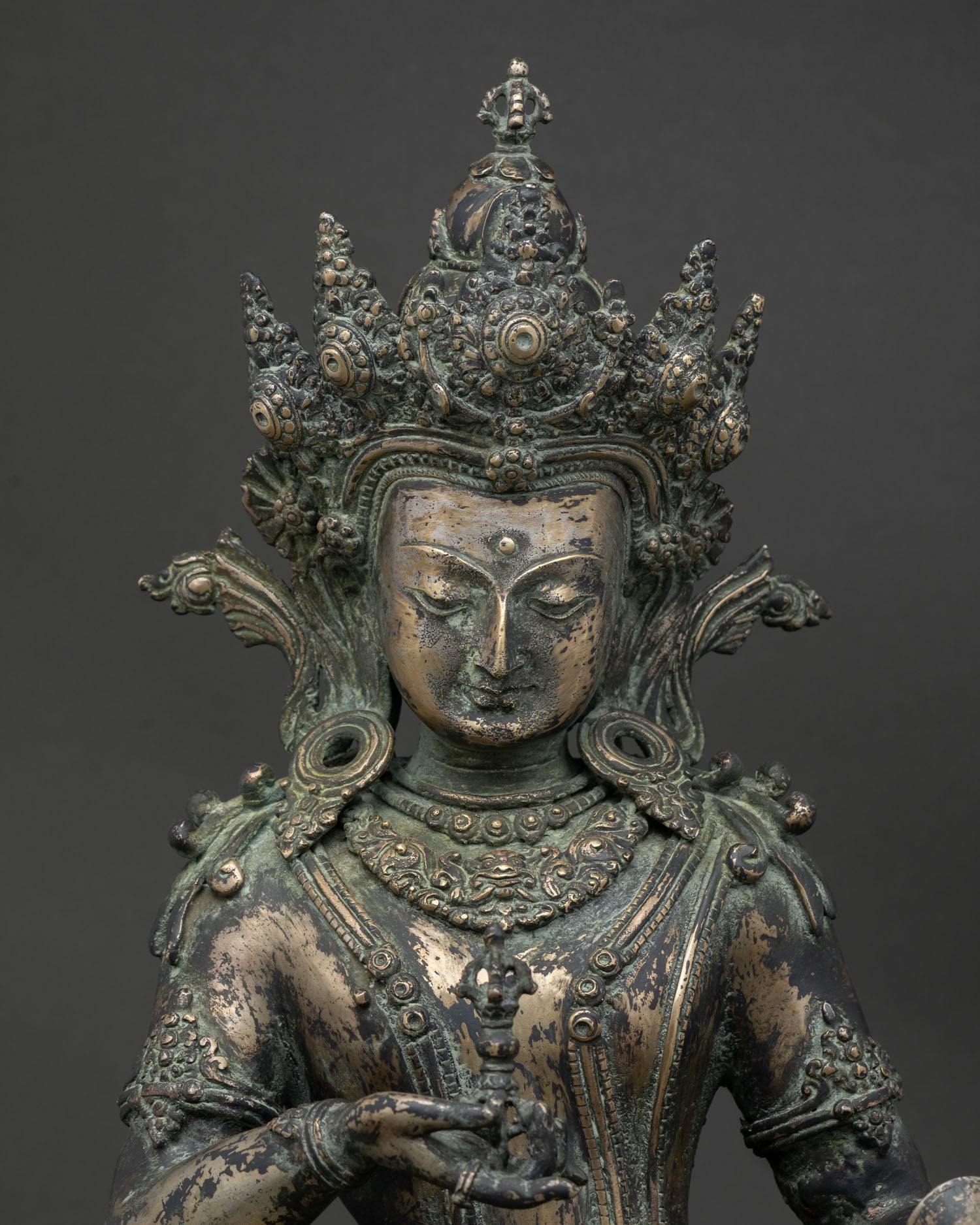 Close-up of Vajrasattva bronze statue showing crown, vajra, and bell detail