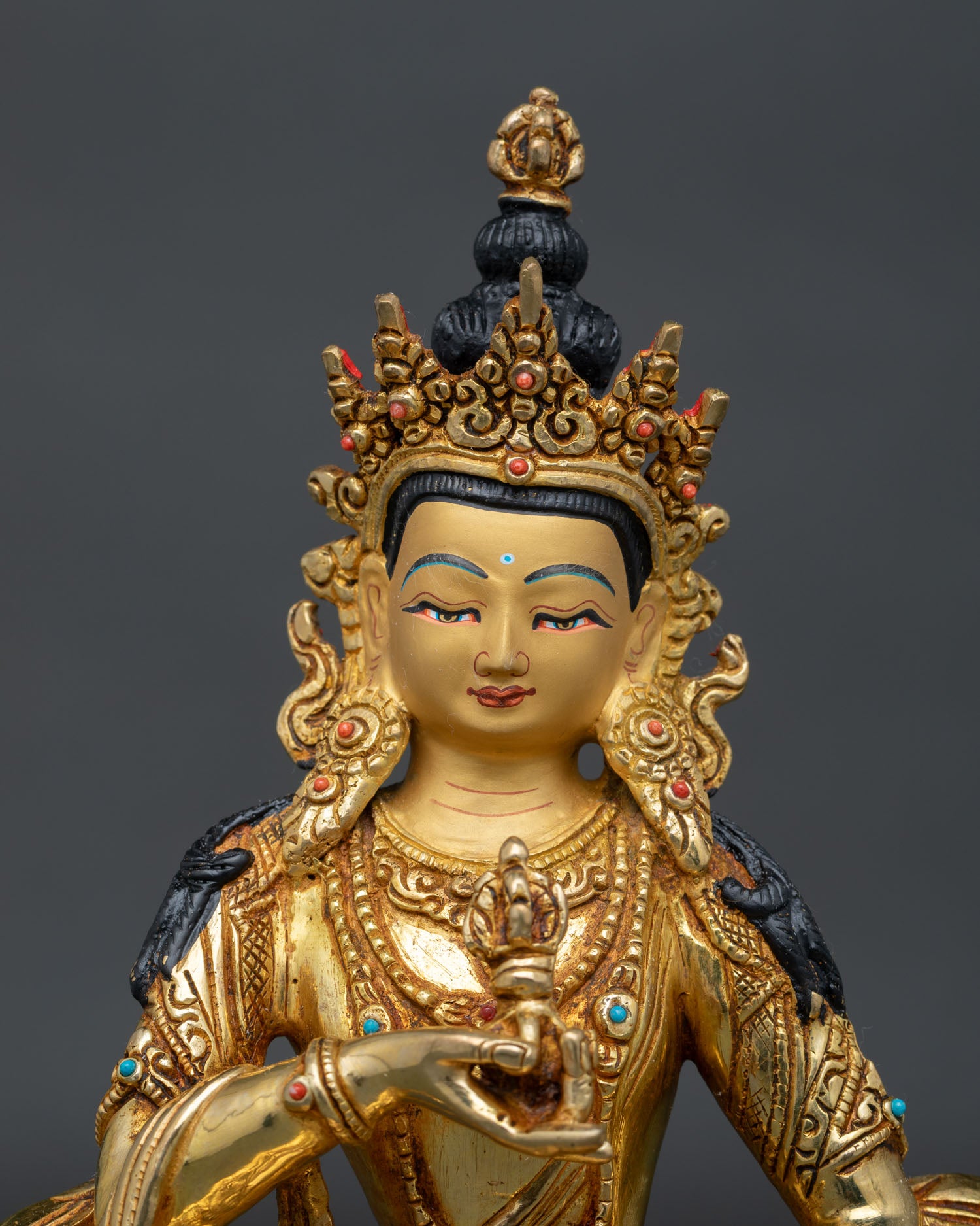 Close up of Vajrasattva statue showing gold painted face and intricate Newari craftsmanship.