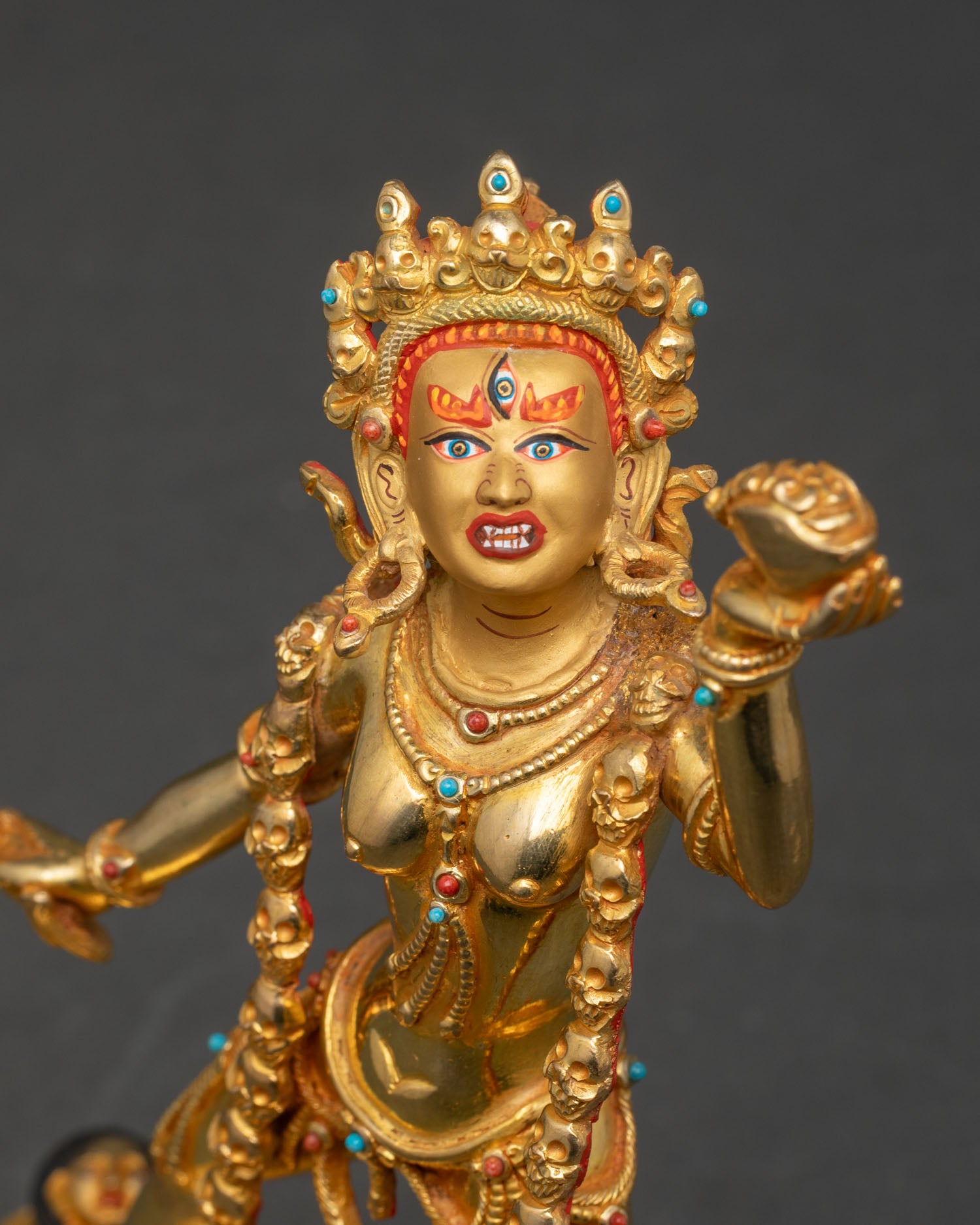 Close up of Vajrayogini face with five skull crown, kartika, and skull cup.