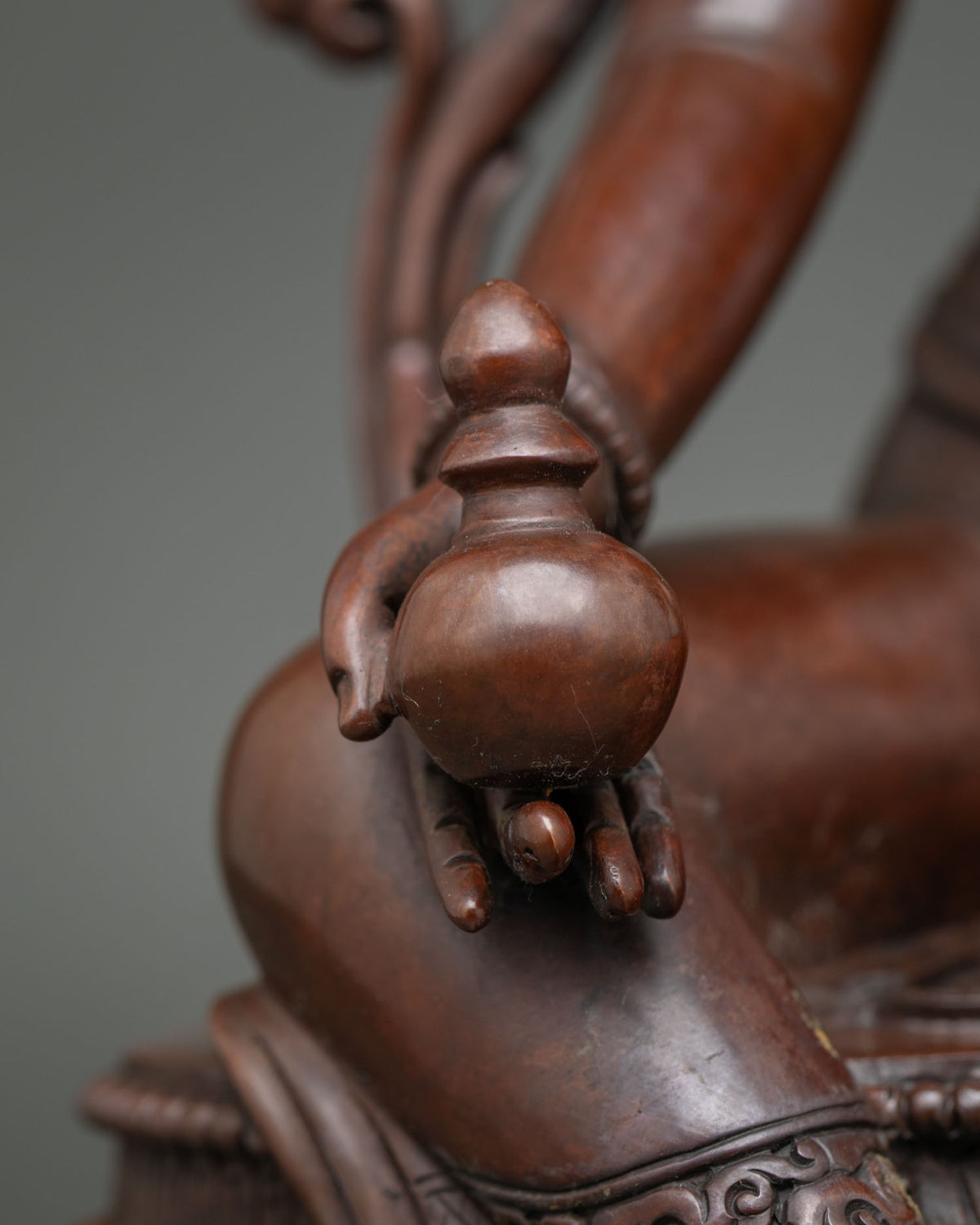 Close-up of vase held in Green Tara statue’s hand on oxidized copper