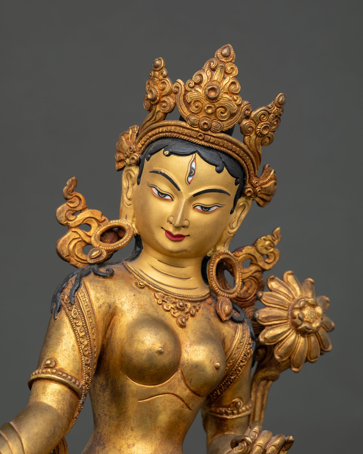 Close up of White Tara Bodhisattva gold painted face and intricate Himalayan artwork details