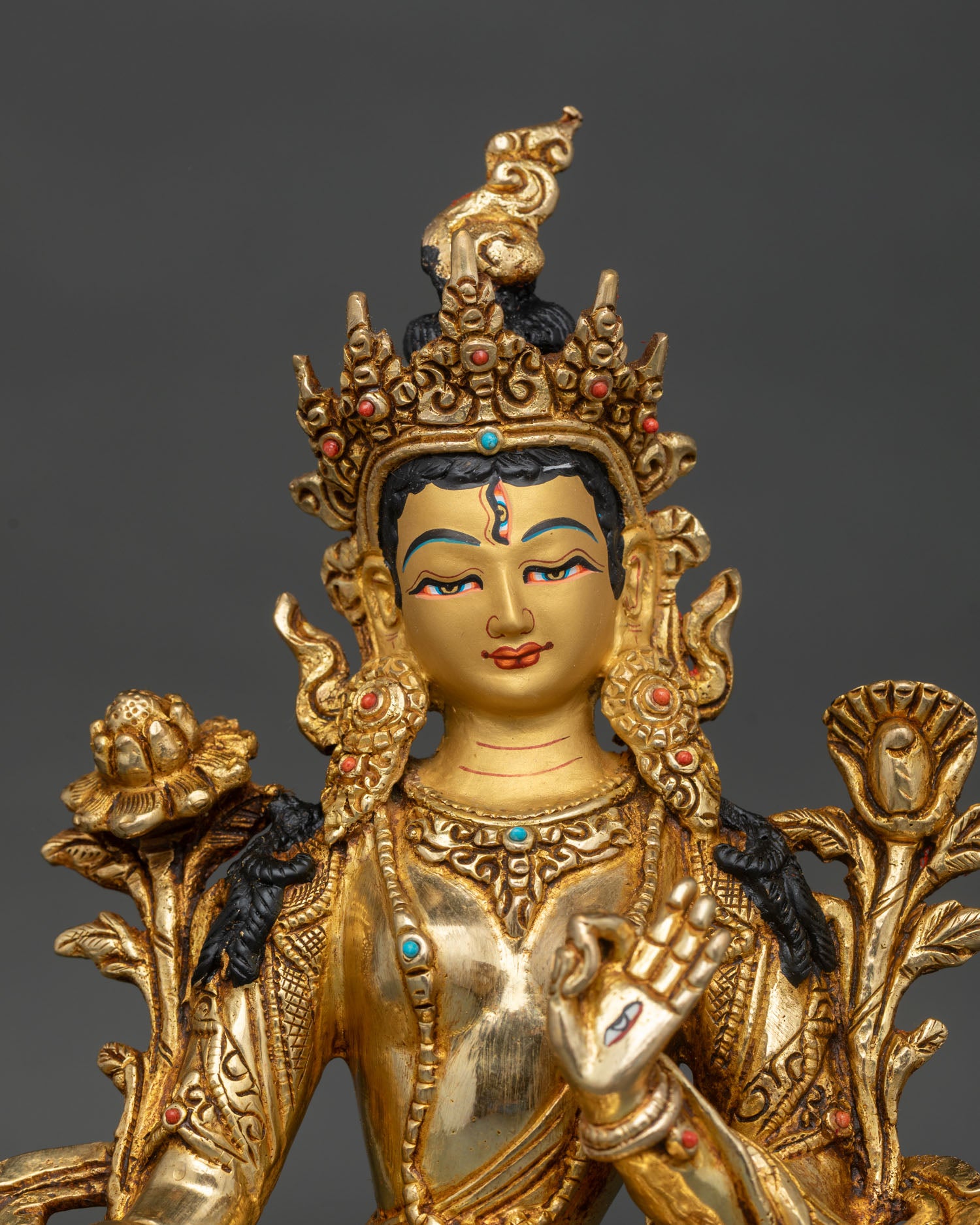 close up of white tara face with gold painted details and seven compassionate eyes