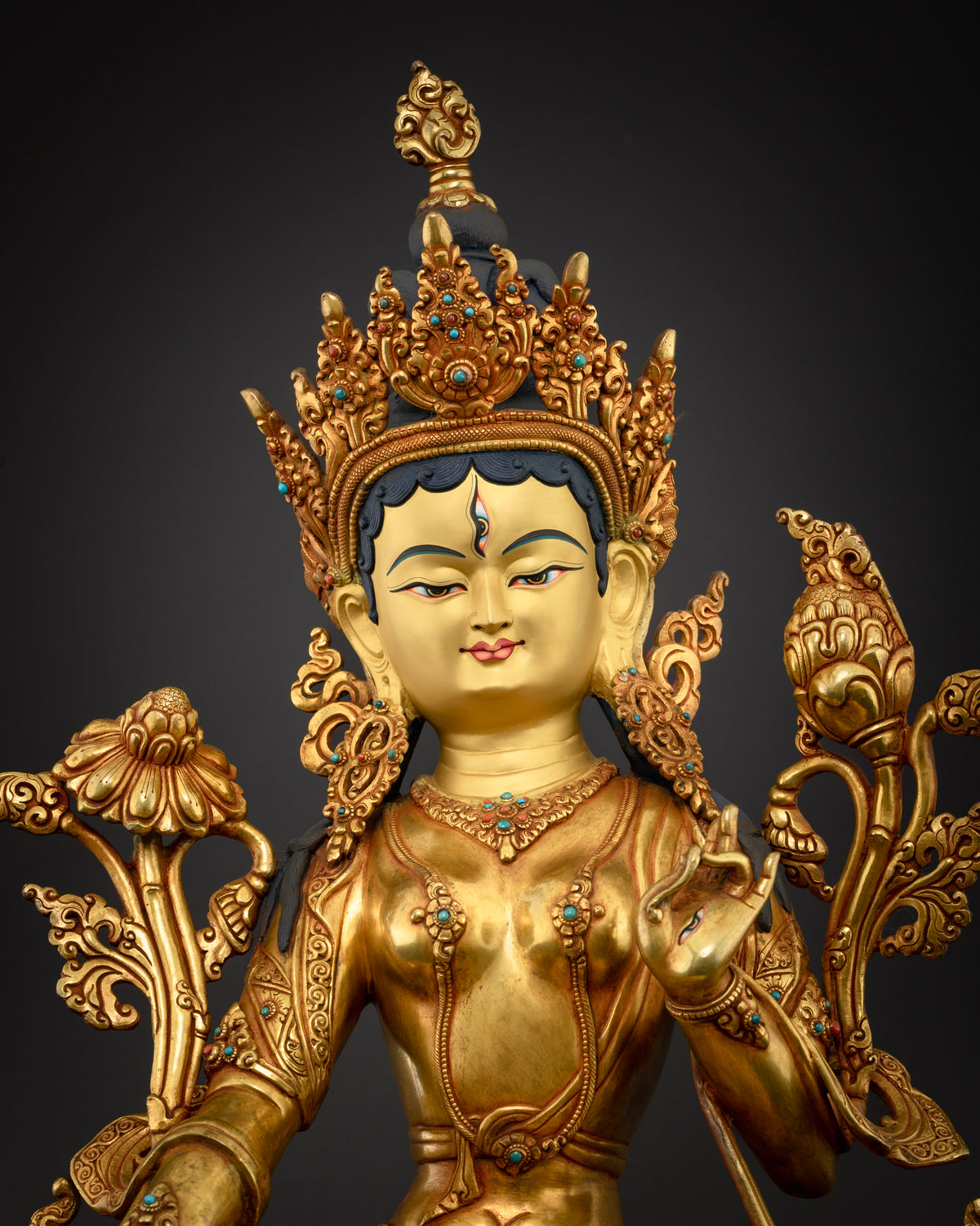 Close-up of White Tara statue face, ornate crown and turquoise-accented gold Buddhist art
