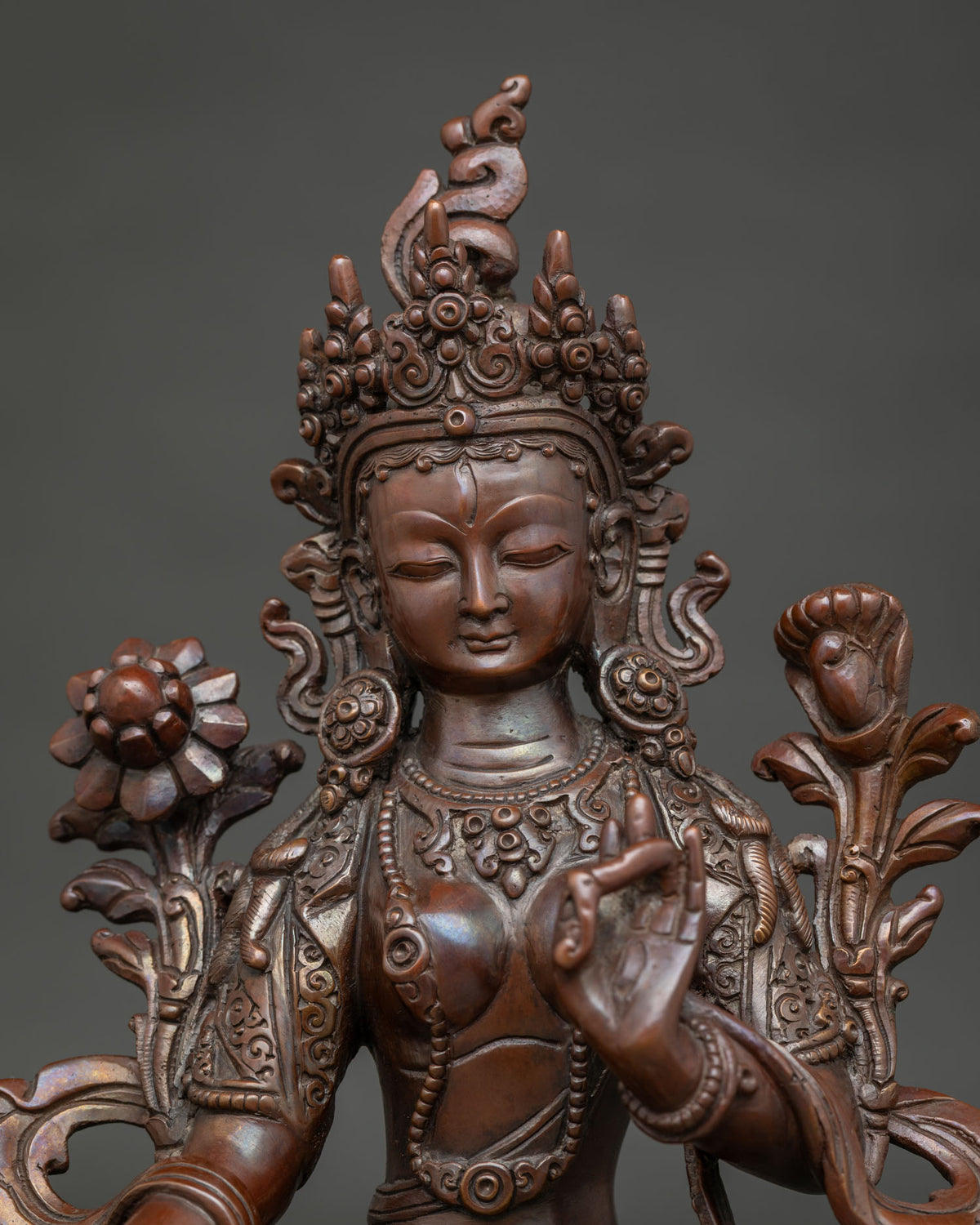 Close up of White tara statue showing serene face and intricate copper craftsmanship.