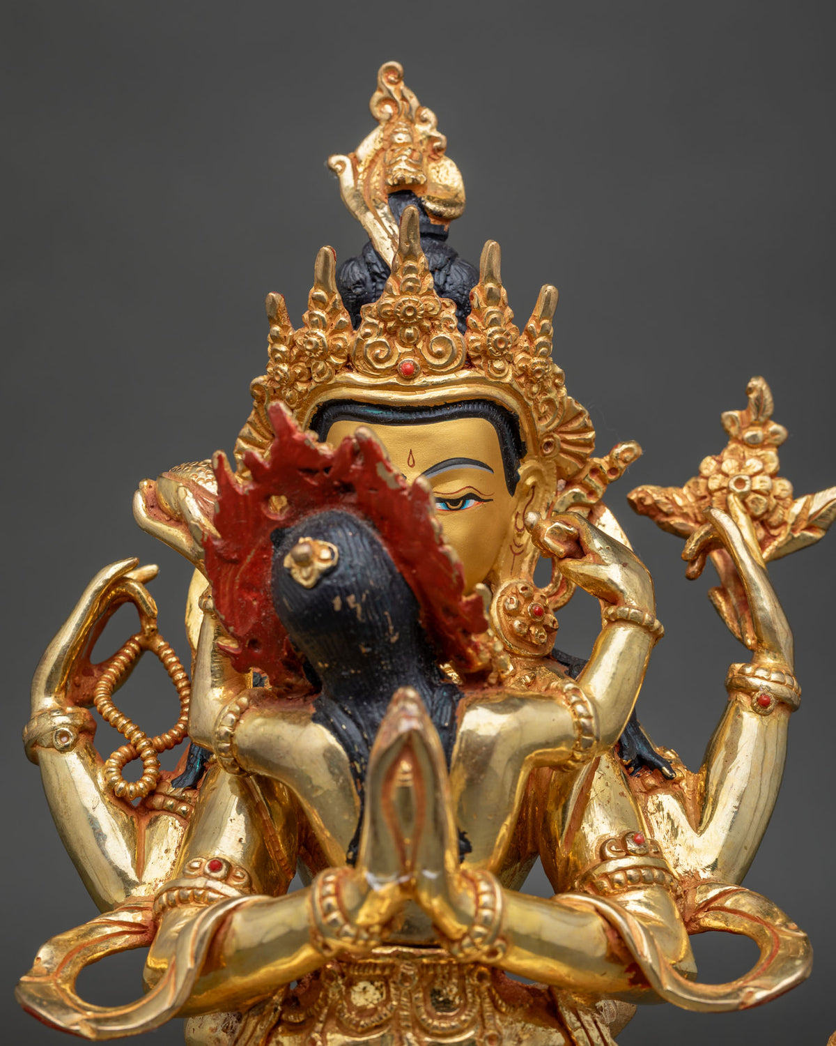 Close-up of Yab-Yum statue showing consort’s dark hair, red flame halo and gilded hands