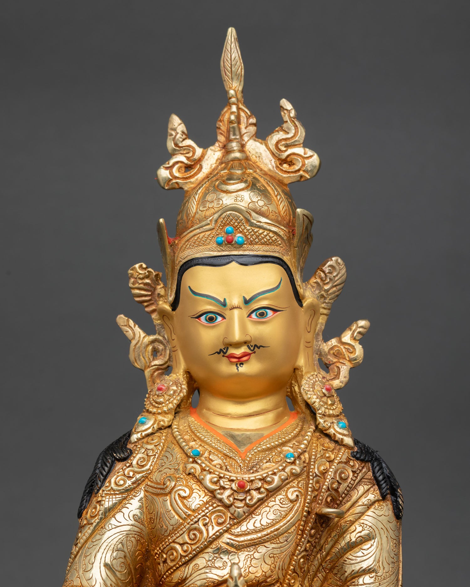 Close up Padmasambhava Guru Rinpoche statue gold painted face semi precious stones intricate Himalayan craftsmanship details