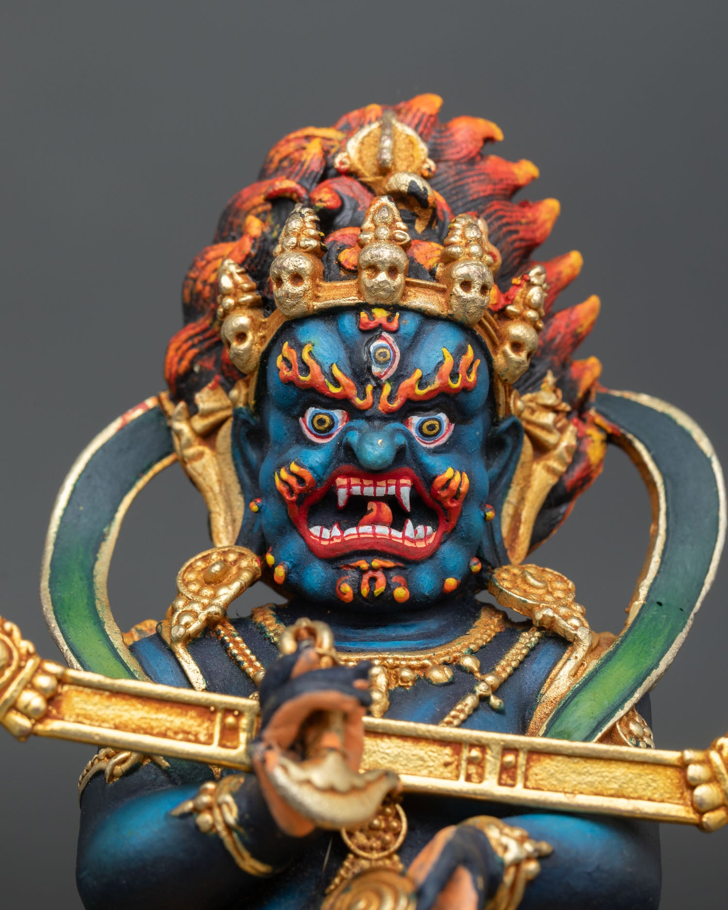 Close up Sakya Mahakala face with three intense eyes crown of five skulls and fierce expression representing enlightened wrathful compassion