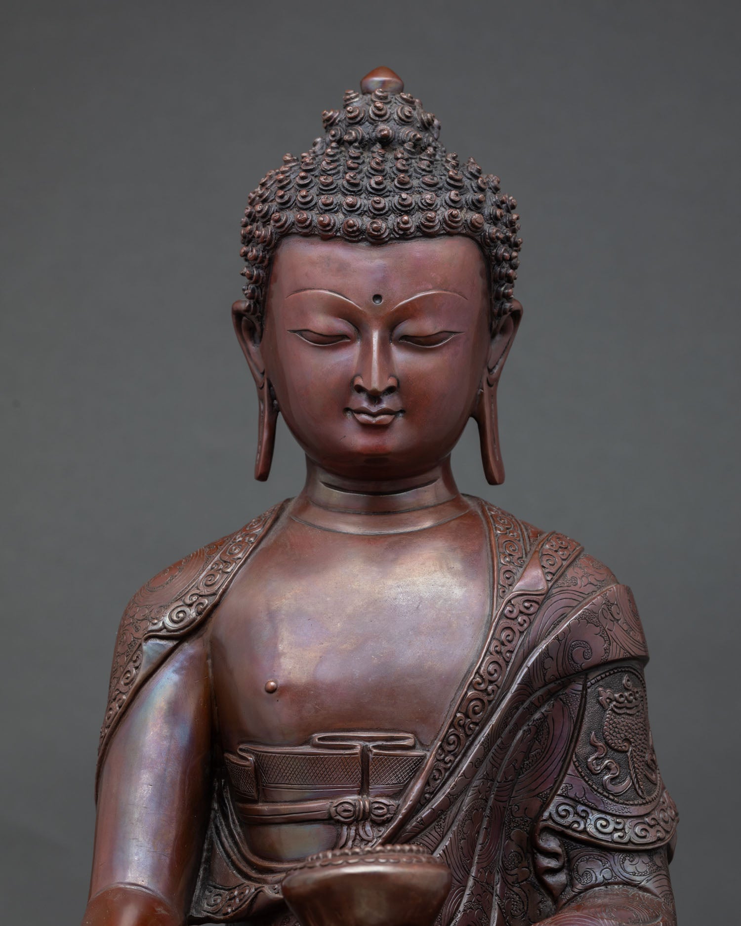 Close-up serene face of Shakyamuni Buddha statue, hand-carved oxidized copper Buddhist sculpture