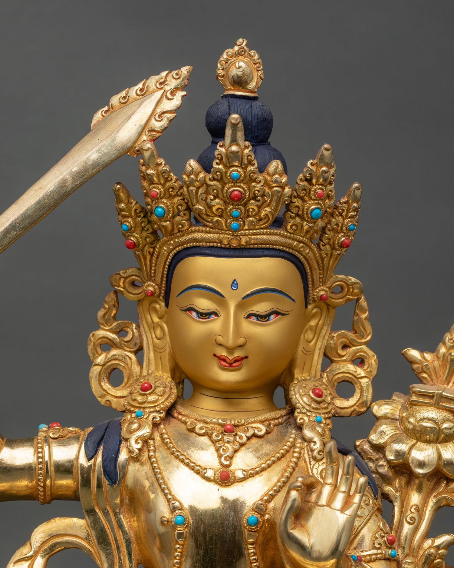 Close up of serene Manjushri face with five-jewel crown and vibrant stones