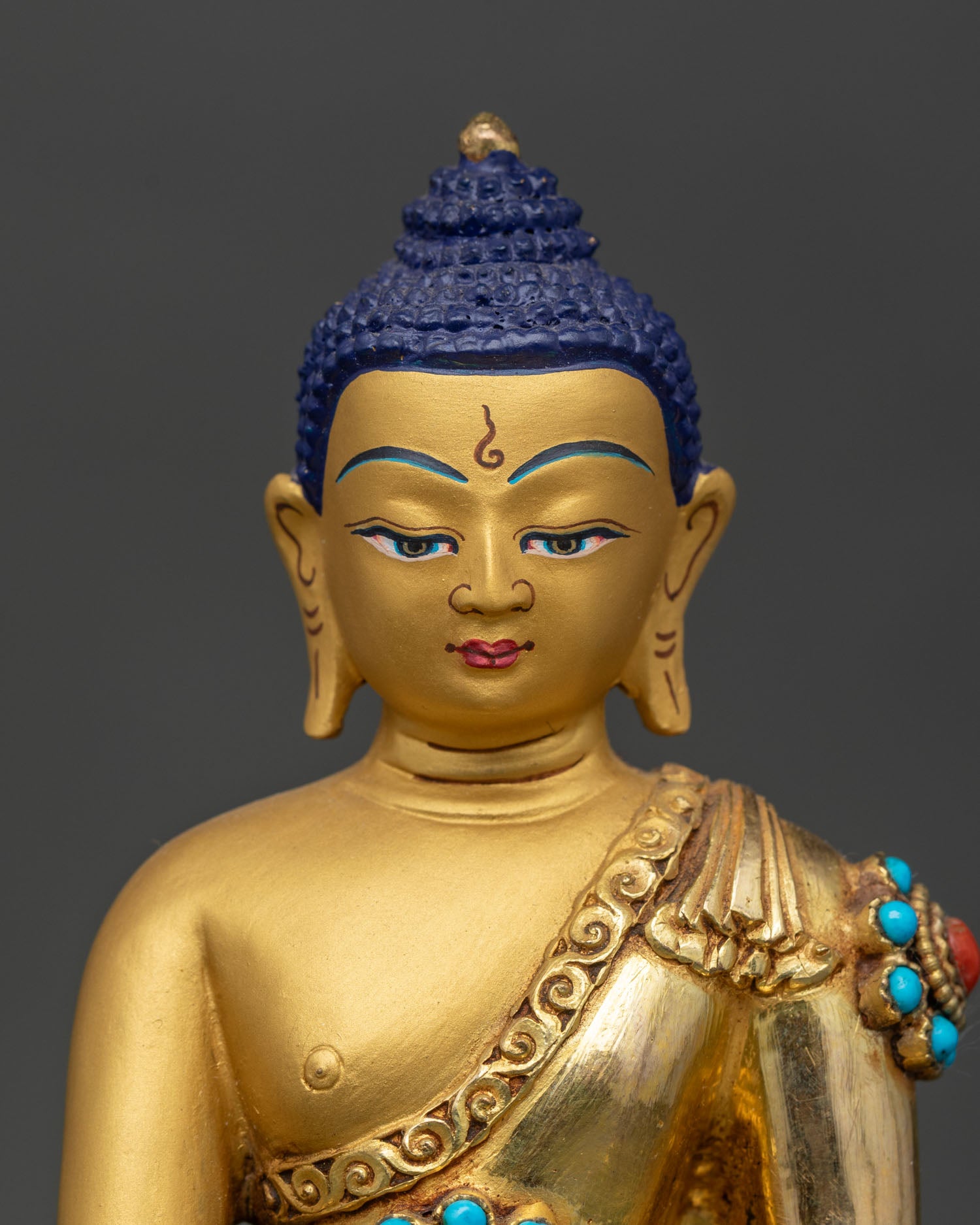 Close up Shakyamuni Buddha face detail gold gilded expression earth touching mudra turquoise coral inlay Newari handcrafted Buddhist sculpture