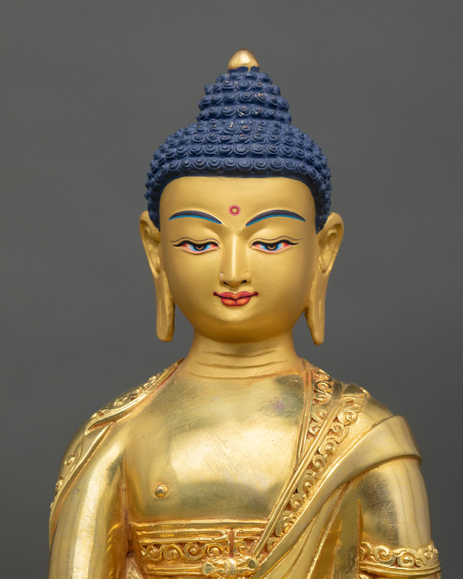 Close up Shakyamuni Buddha face gold painted serene expression Himalayan Newari craftsmanship Patan Buddhist sacred art detail