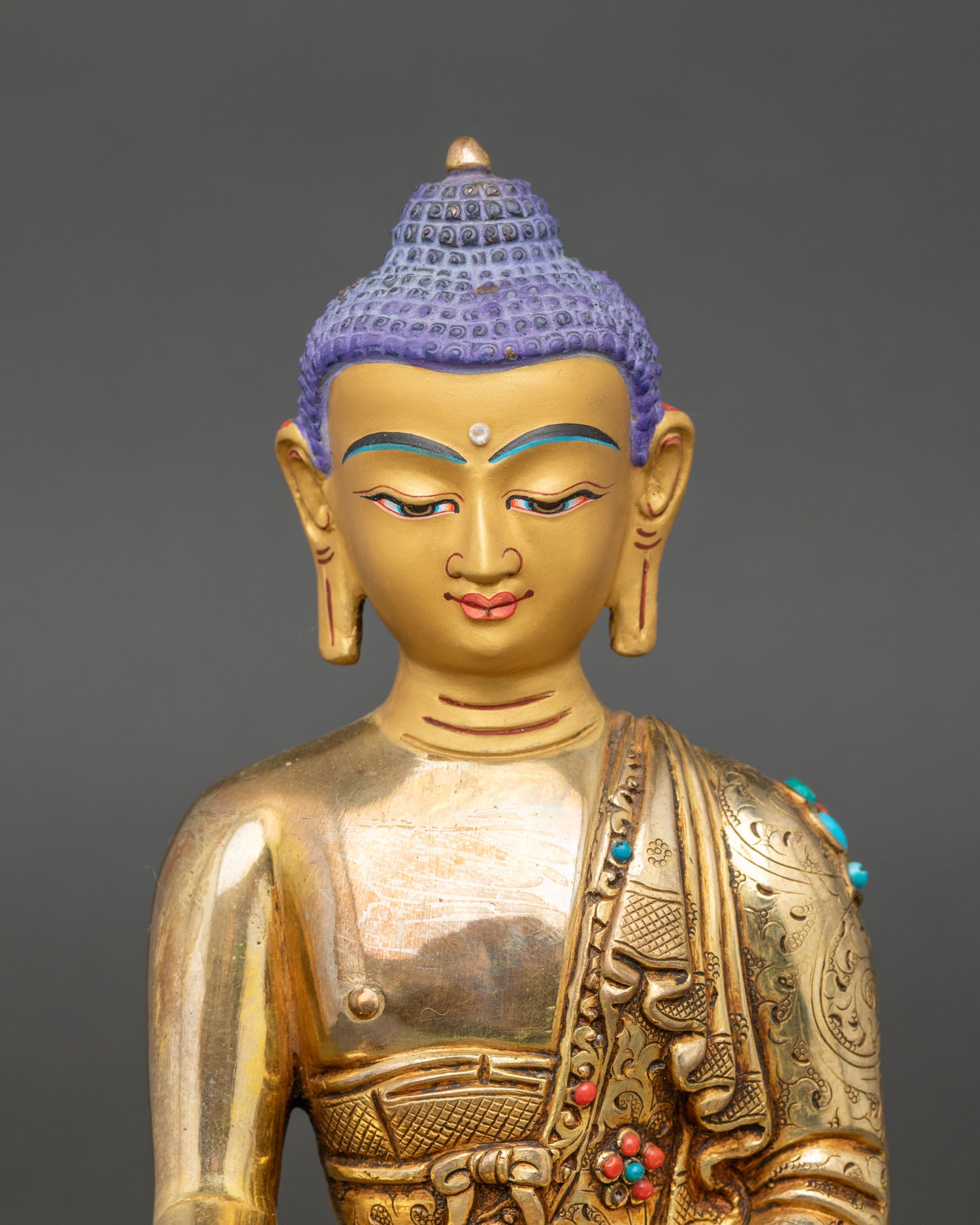 Close up of Shakyamuni Buddha face serene expression gold painted copper Himalayan sculpture