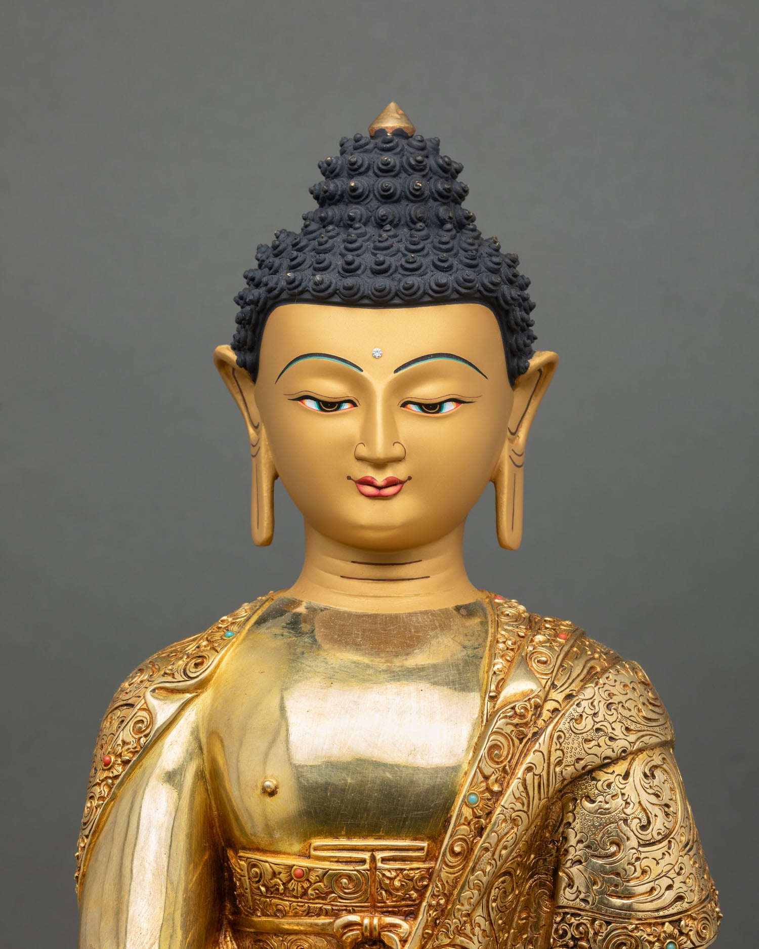 Close up of Shakyamuni Buddha gold painted face with semi precious stone details