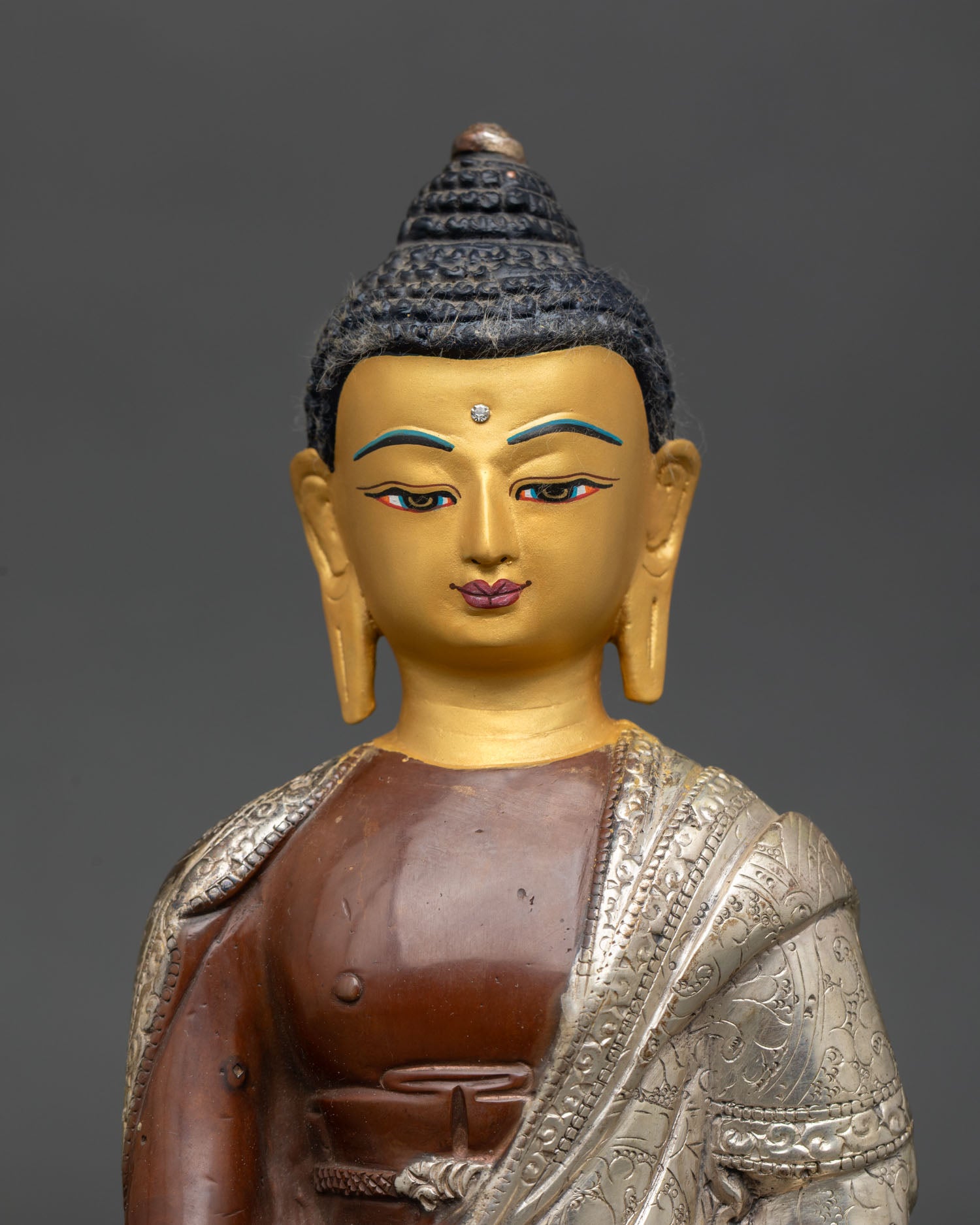 Close up Shakyamuni Buddha gold painted serene face detail copper statue with oxidized silver plated finish