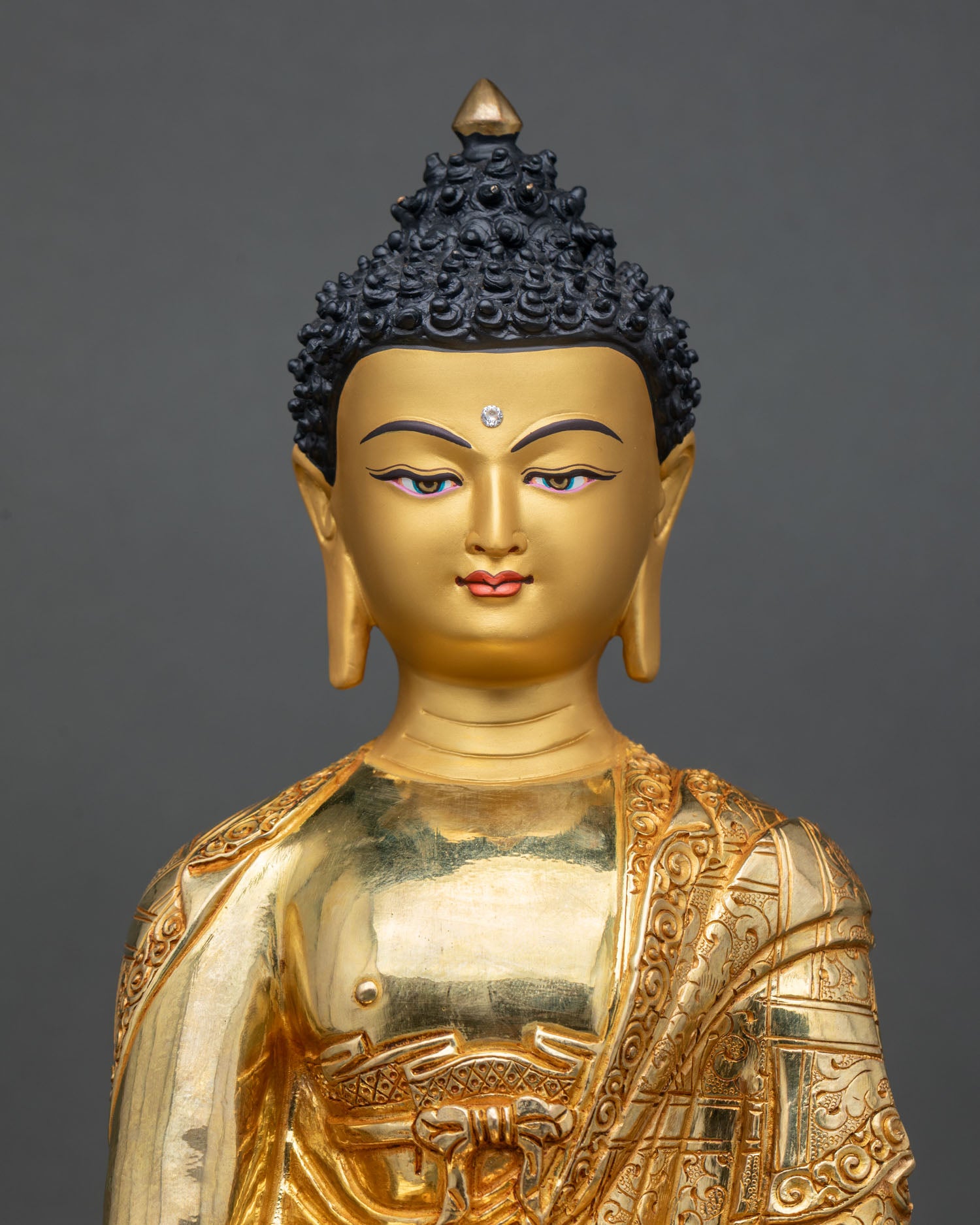 Close up Shakyamuni Buddha sculpture with detailed gold painted face, traditional Himalayan craftsmanship in copper and gold finish