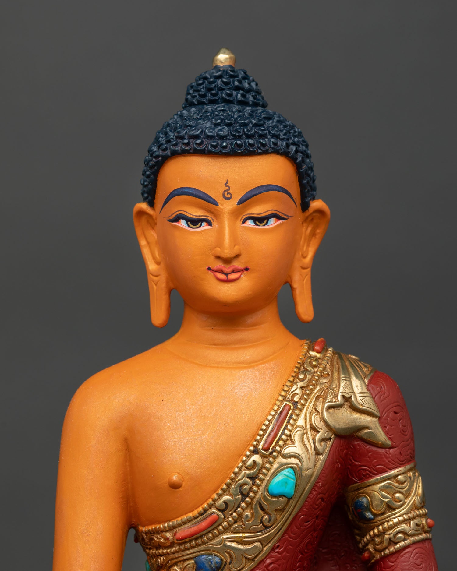 Close up Shakyamuni Buddha serene face gold painted details acrylic finishing Himalayan Buddhist art meditation enlightenment statue