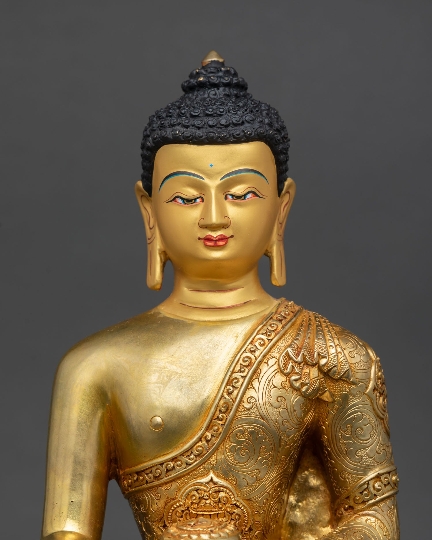 Close up Shakyamuni Buddha statue with gold painted face serene expression and detailed Nepalese craftsmanship using lost wax casting method