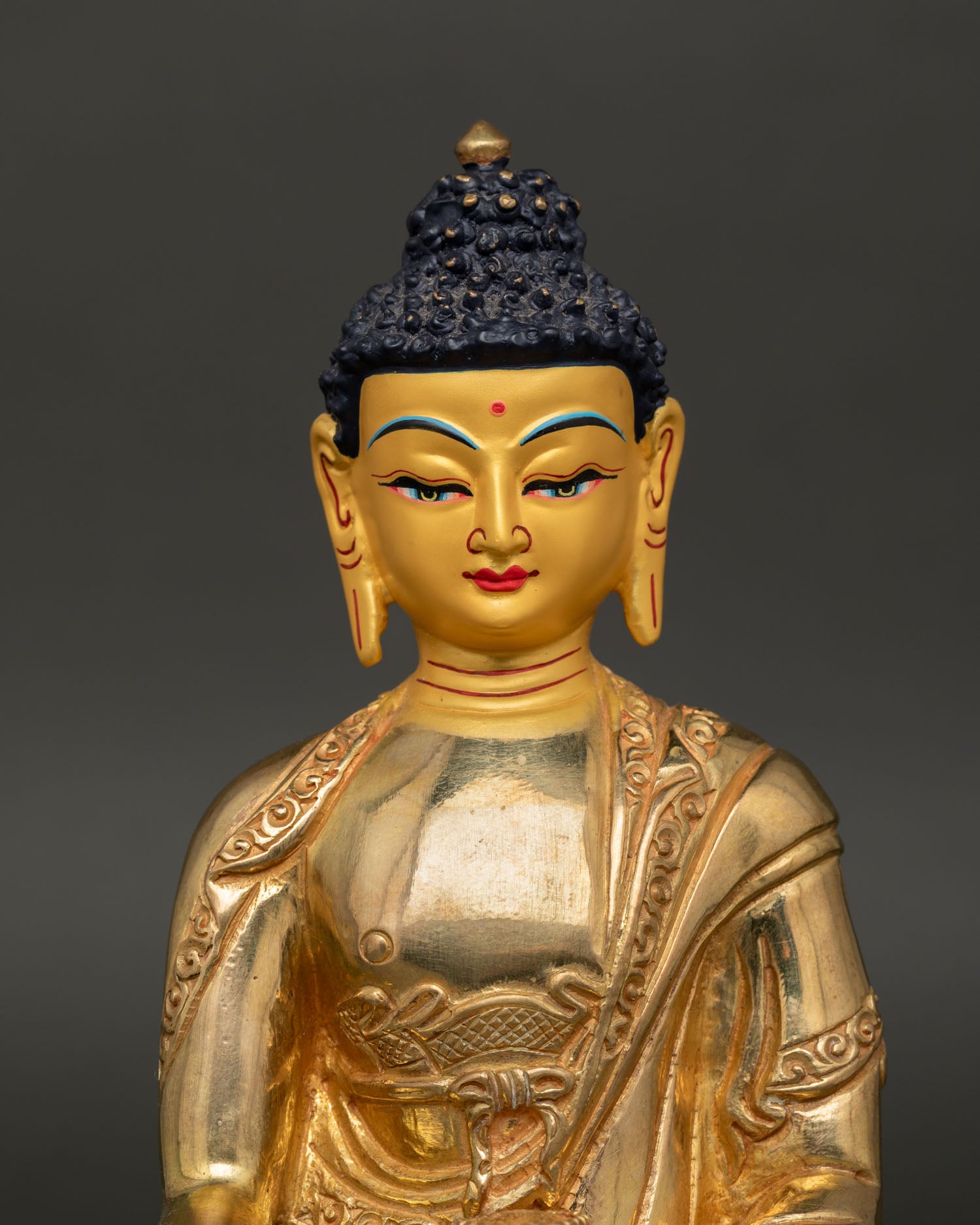 Close up Shakyamuni Buddha Statue with gold painted face showing Bhumisparsha Mudra and serene enlightened expression