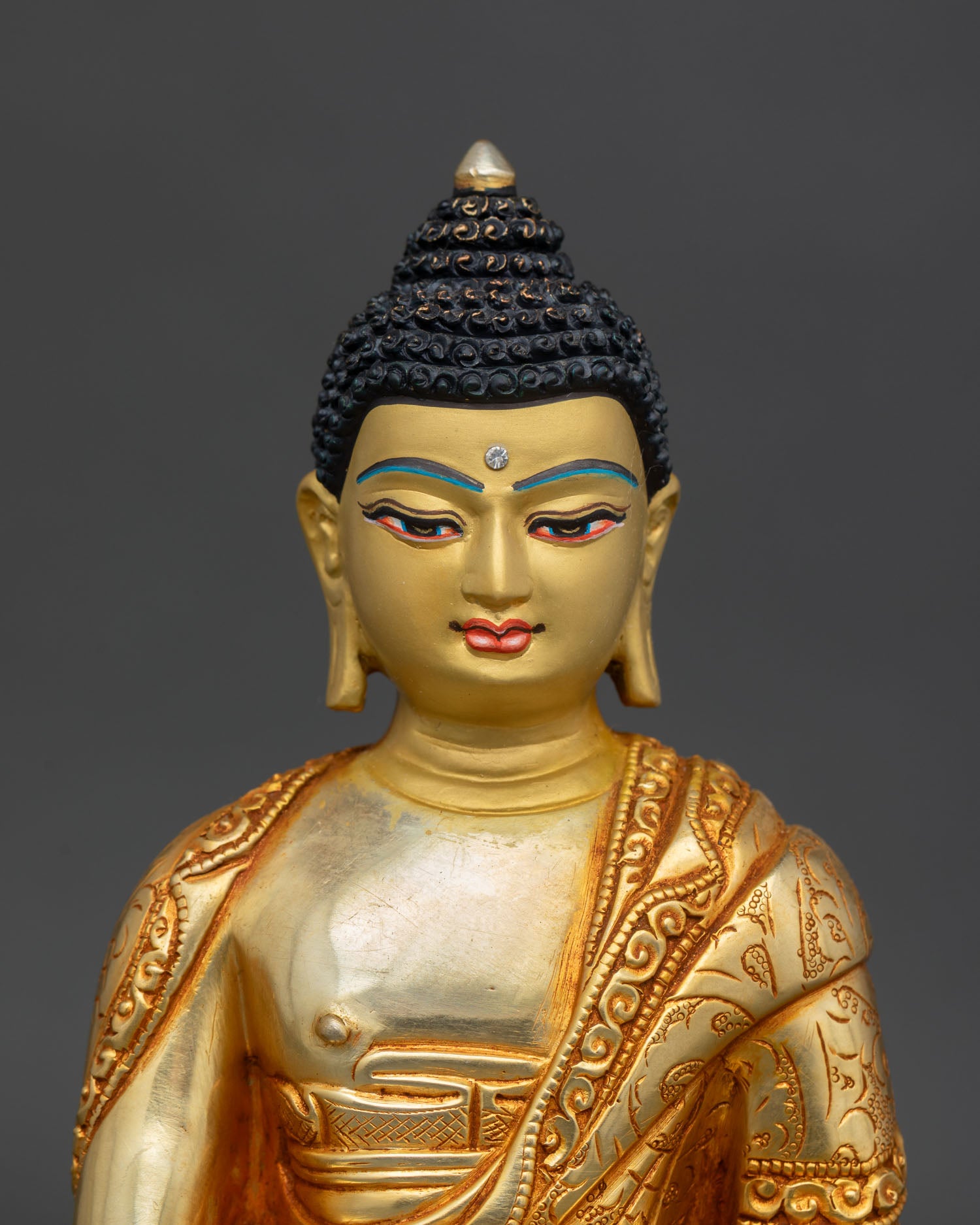 Close up Shakyamuni Buddha statue with serene gold painted face copper Himalayan Buddhist artwork lost wax casting detail