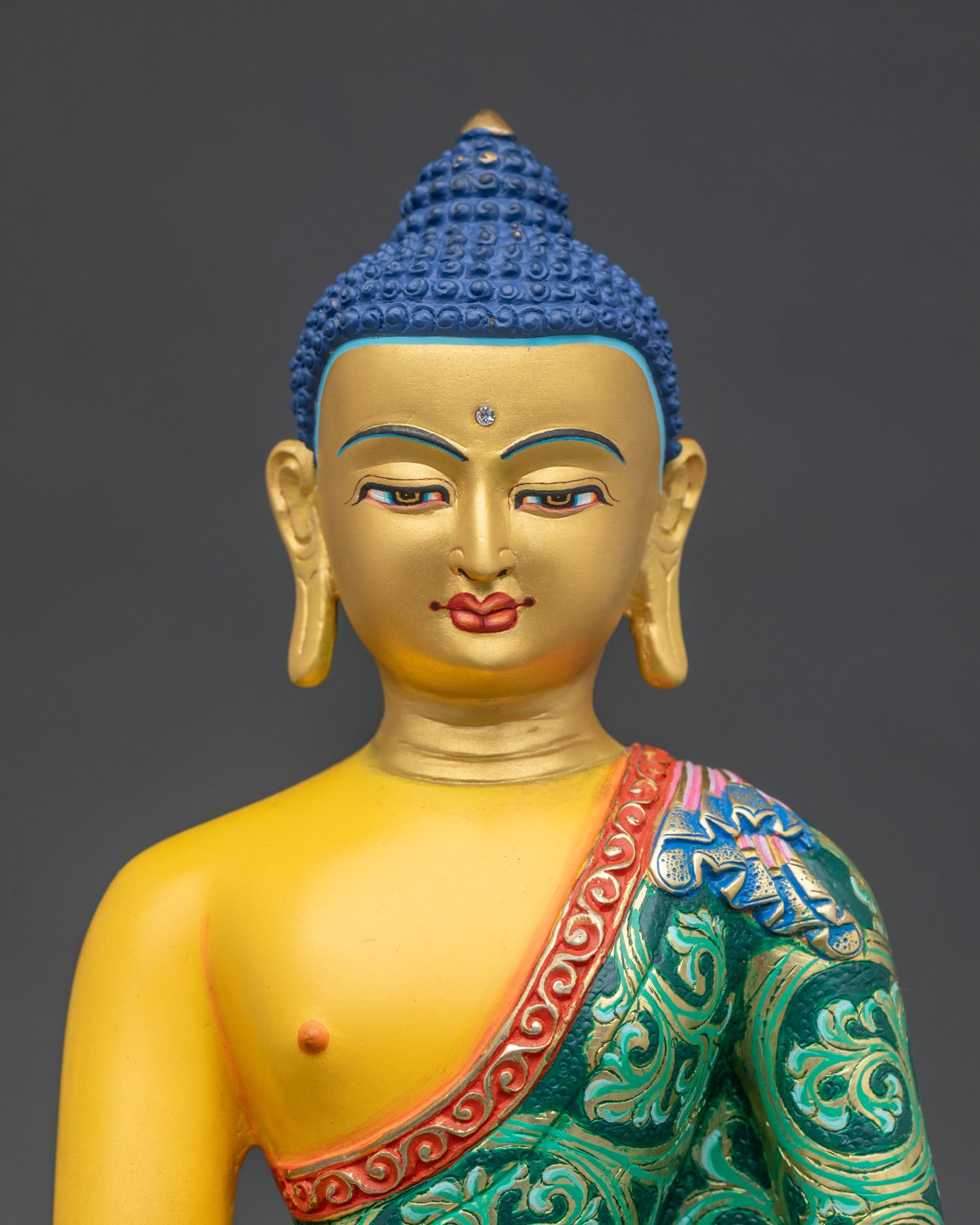 Close up Shakyamuni Buddha statue with serene gold painted face hand applied acrylic details and carved monastic robes