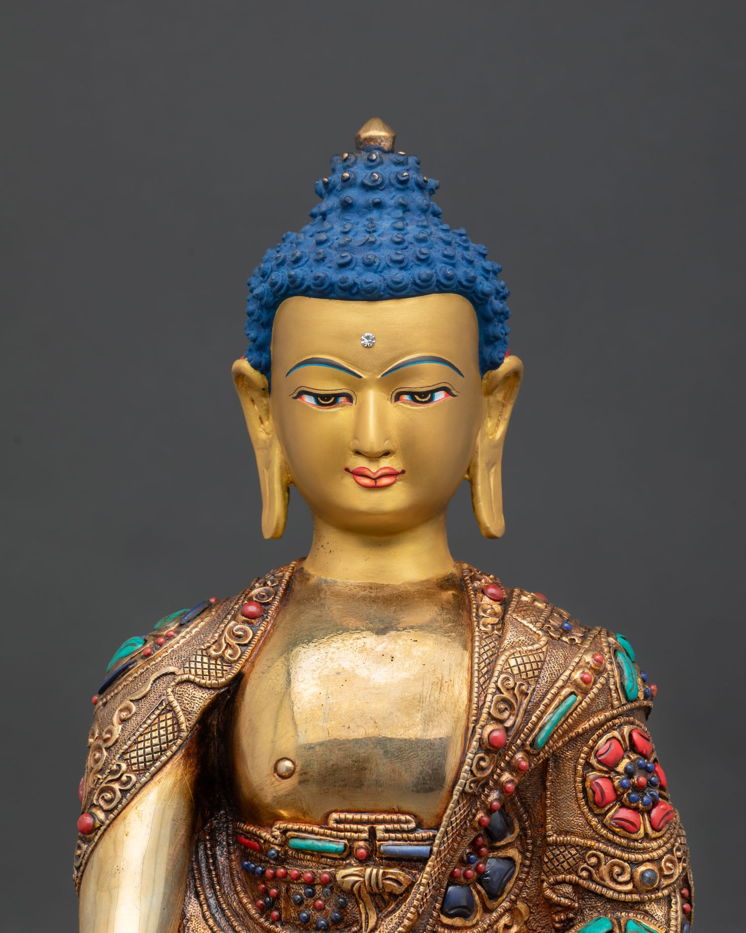 Close up view of Siddhartha Gautama Buddha statue serene face semi precious stones monastic robe Himalayan art