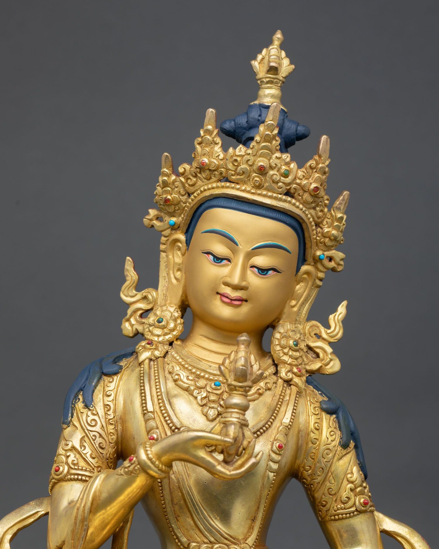 Close up Vajrasattva Buddhist deity face with gold painted details ornate crown and spiritual symbolism