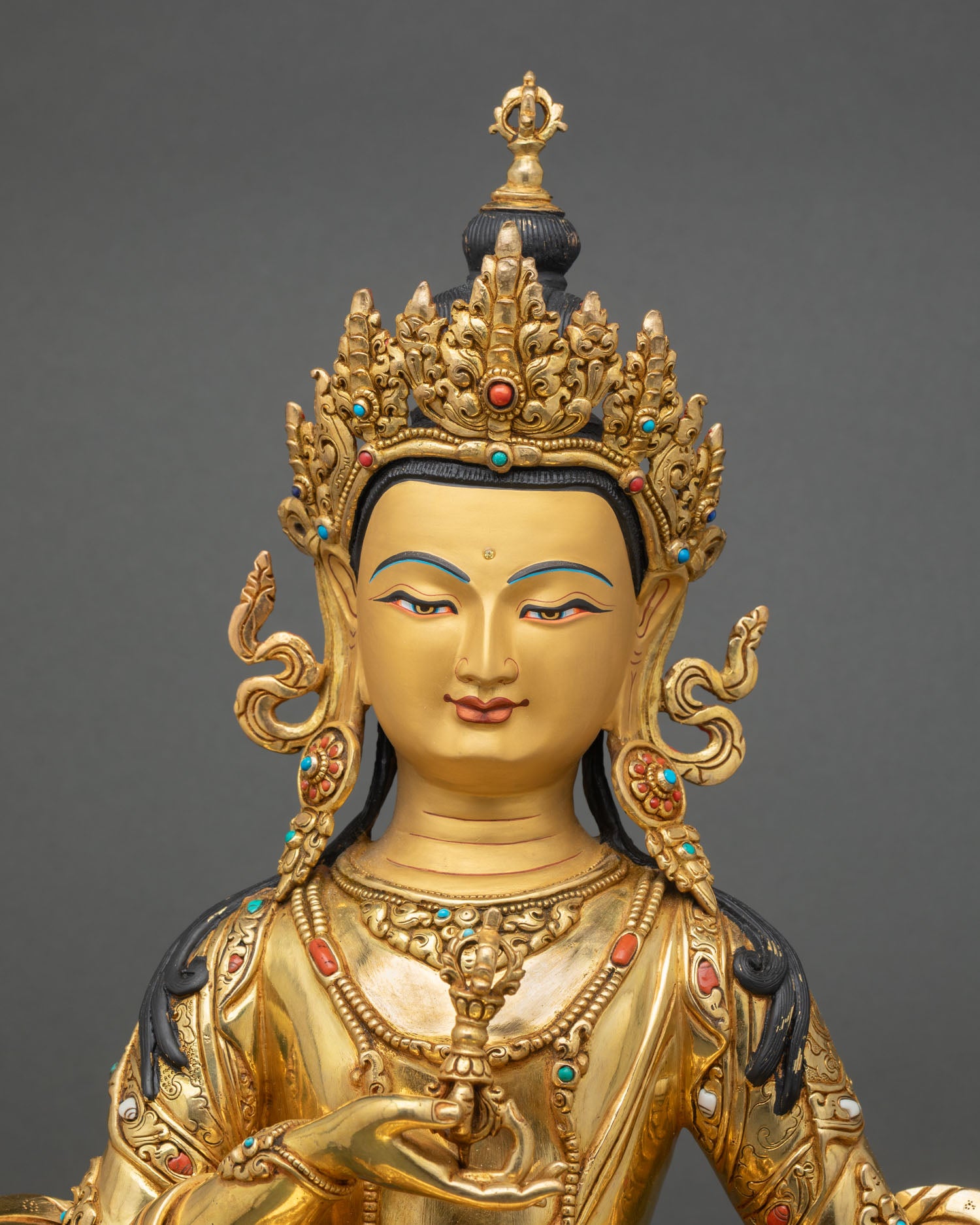 Close up Vajrasattva deity face with gold painted details and jeweled crown