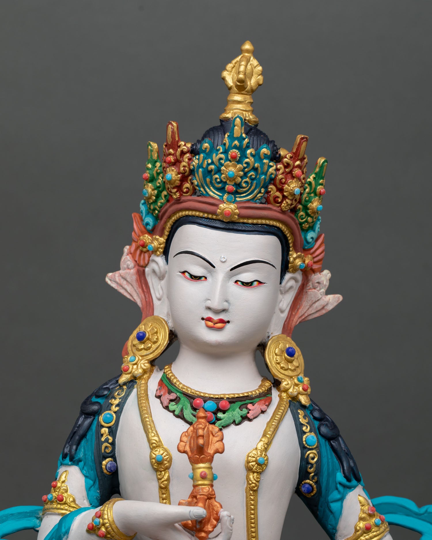 Close-up Vajrasattva face with peaceful expression gold-accent jewelry semi-precious stone detailing Vajrayana meditation sculpture