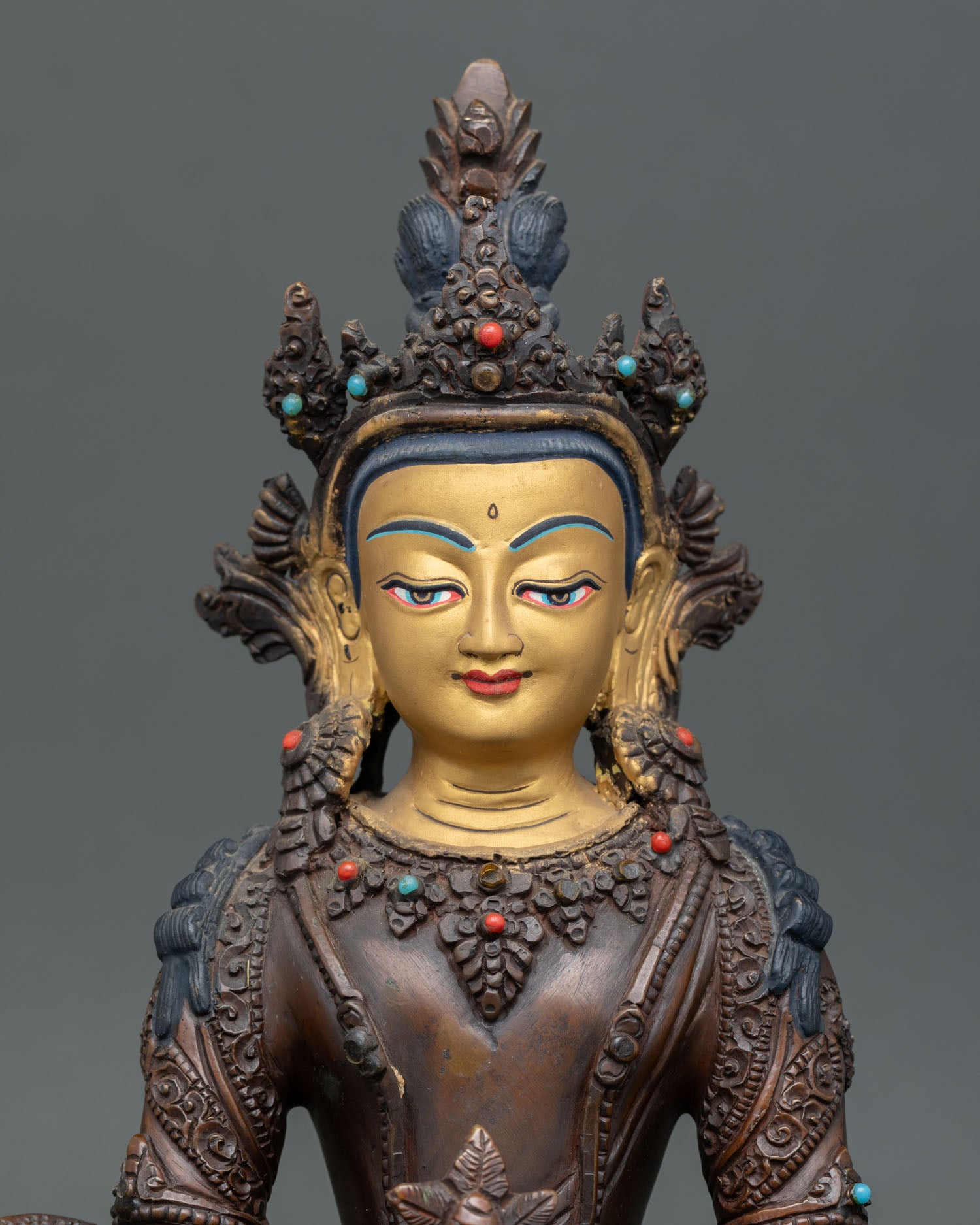 Close up view of Amitayus Buddha gold painted face with semi precious stone adornments.