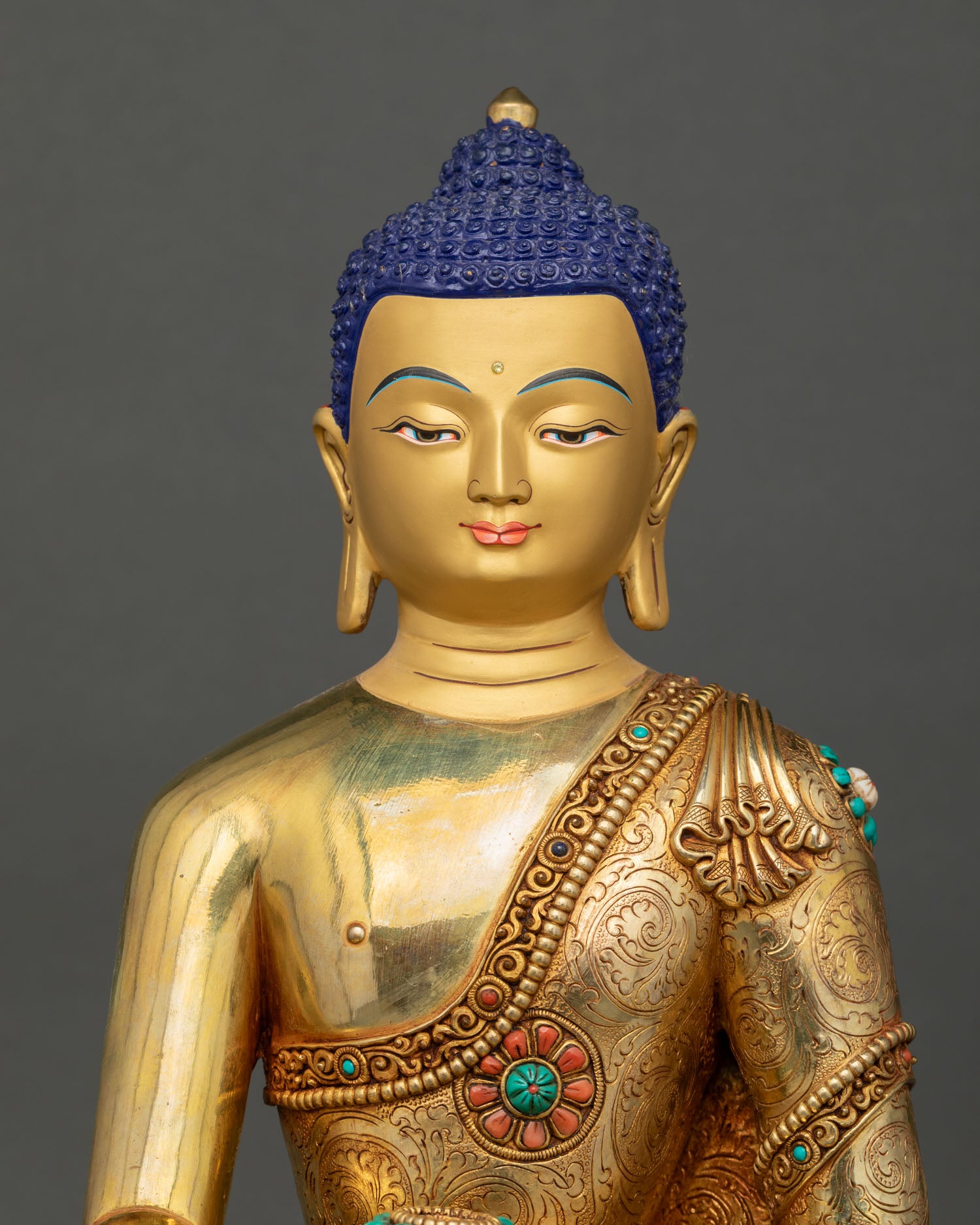 Close up view of Buddha Shakyamuni statue featuring a serene gold painted face, semi precious stones, and traditional Buddhist artistry.