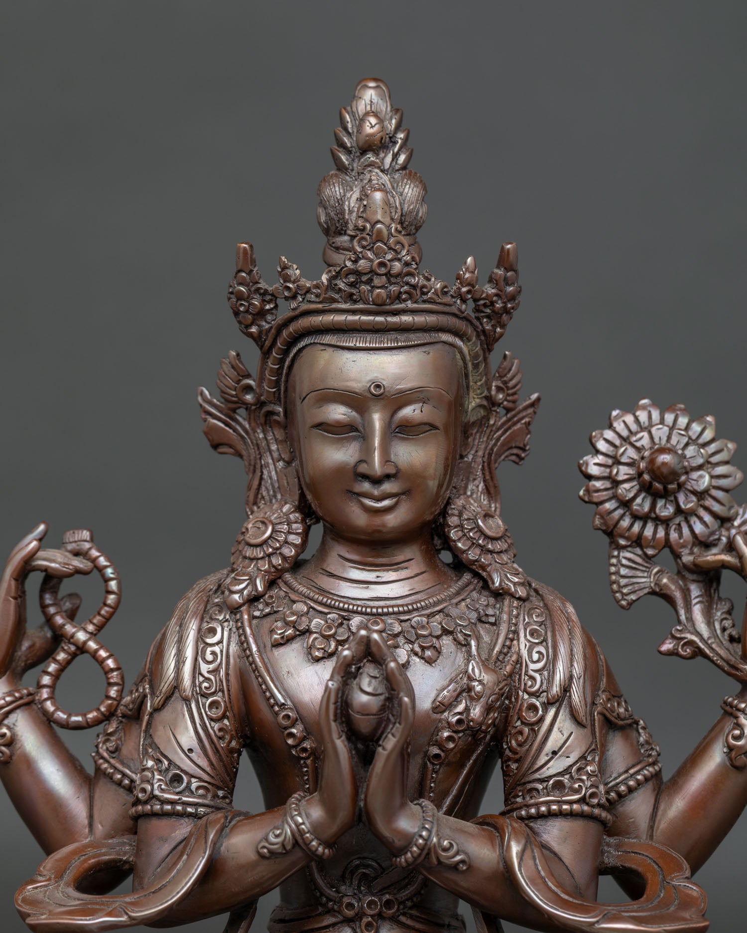 Close up view of Chenrezig statue holding crystal rosary and utpala flowers
