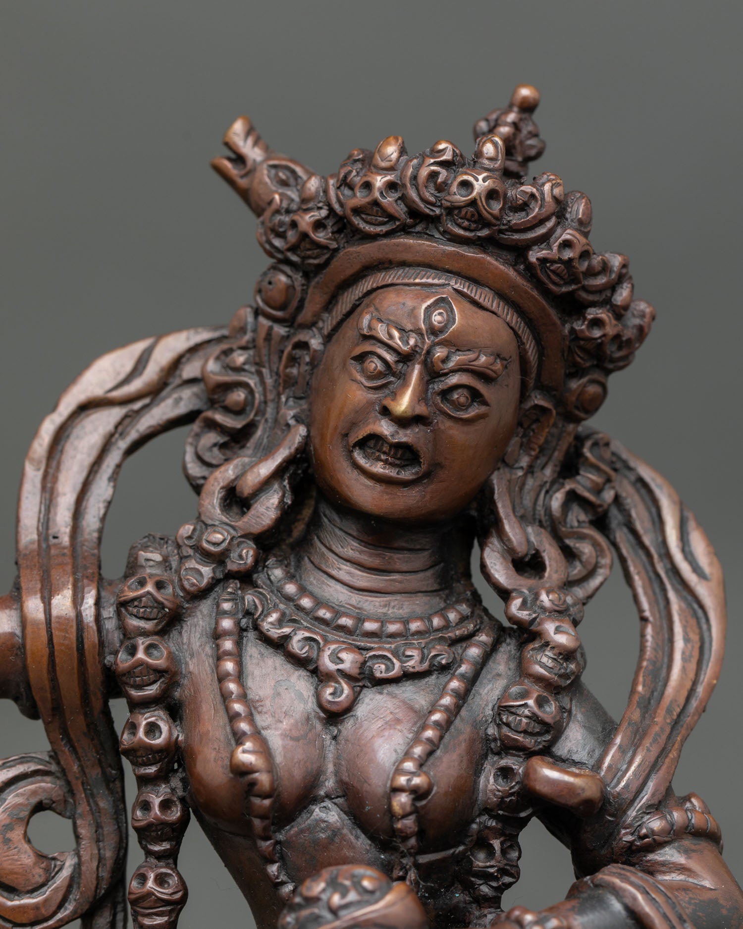 Close up view of Dorje Phagmo face with flaming halo and jeweled crown, sacred Vajrayana goddess statue crafted in copper by Nepalese artisans.