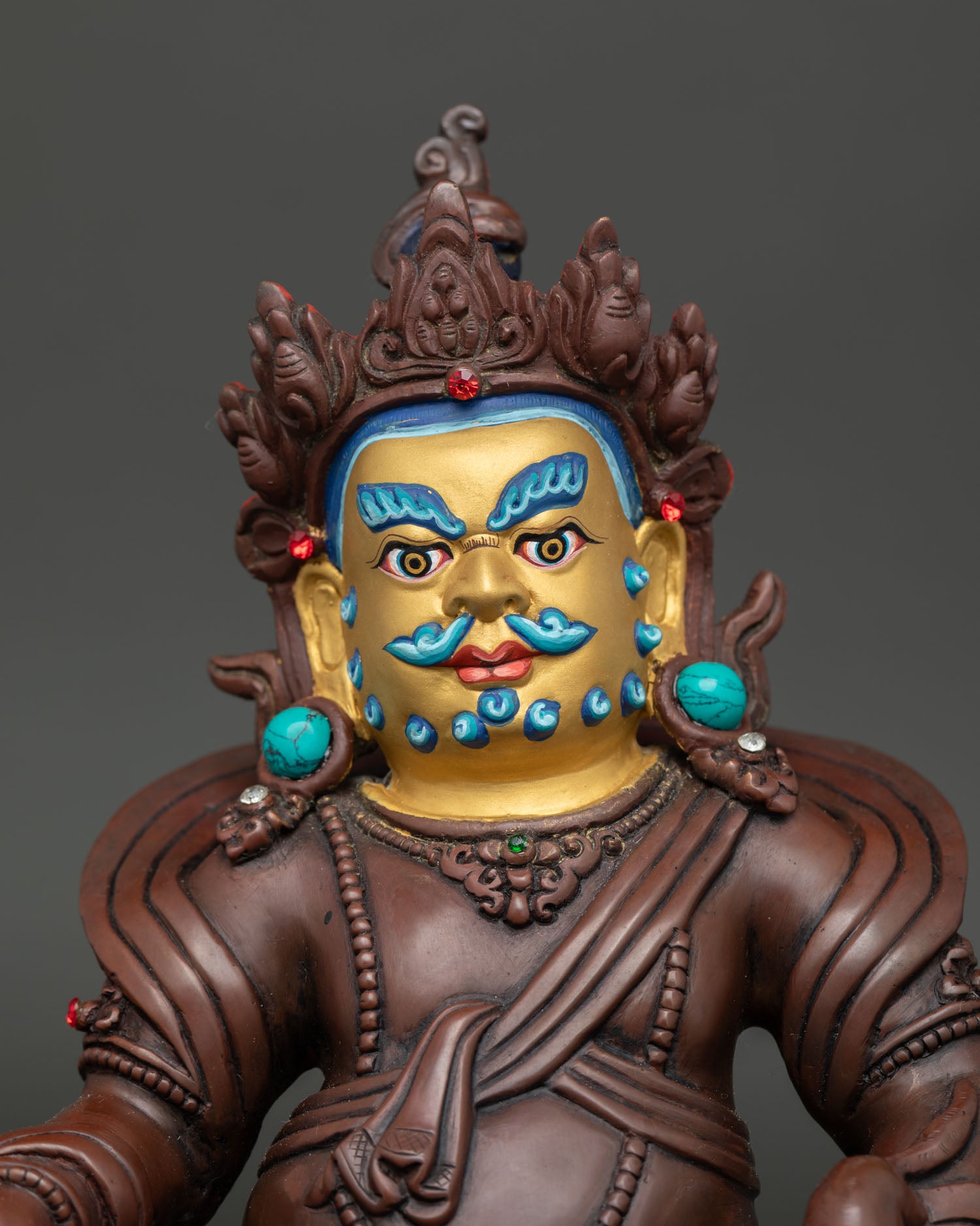 Close up view of Dzambhala Buddhist wealth deity statue with semi precious stone details.