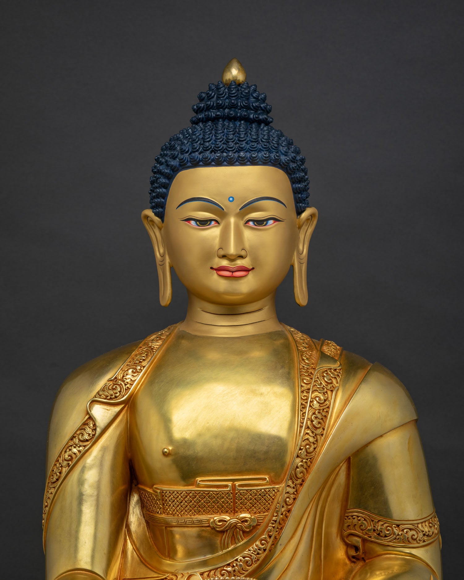 Close-up view of gold gilded Shakyamuni Buddha statue showing detailed robe and serene expression