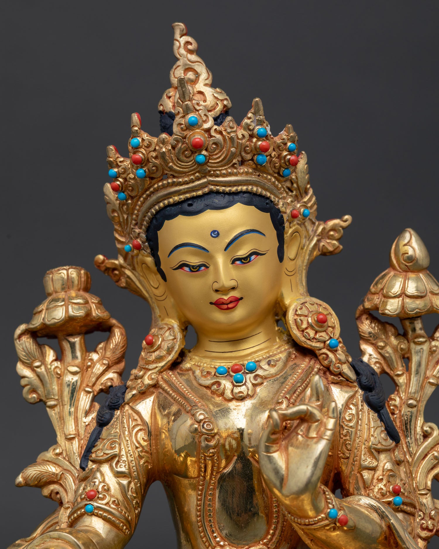 Close up view of Green Tara statue with serene gold painted face symbolizing compassion and protection