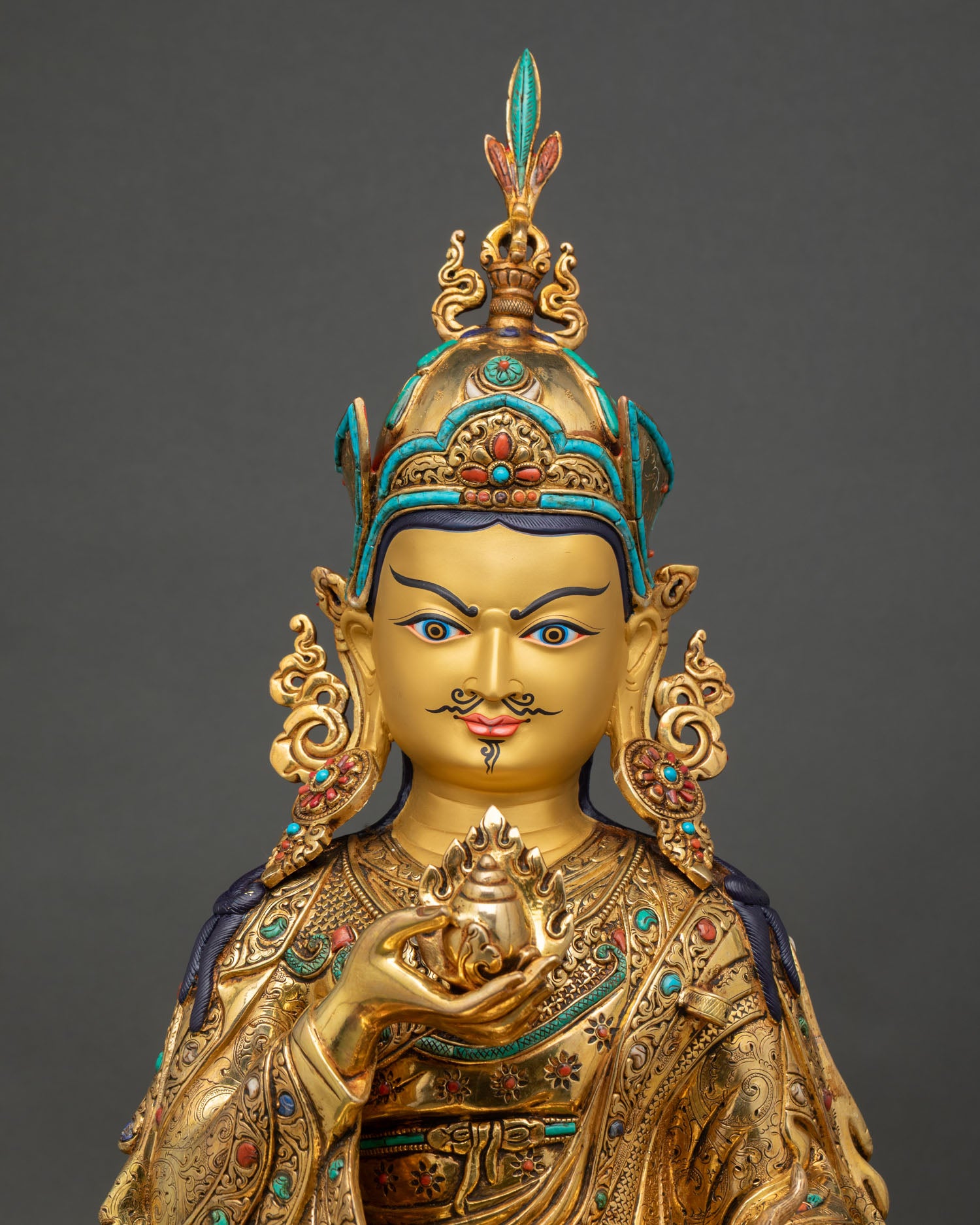 close up view of guru orgyen norlha statue showing intricate gold gilded details and gemstone inlays