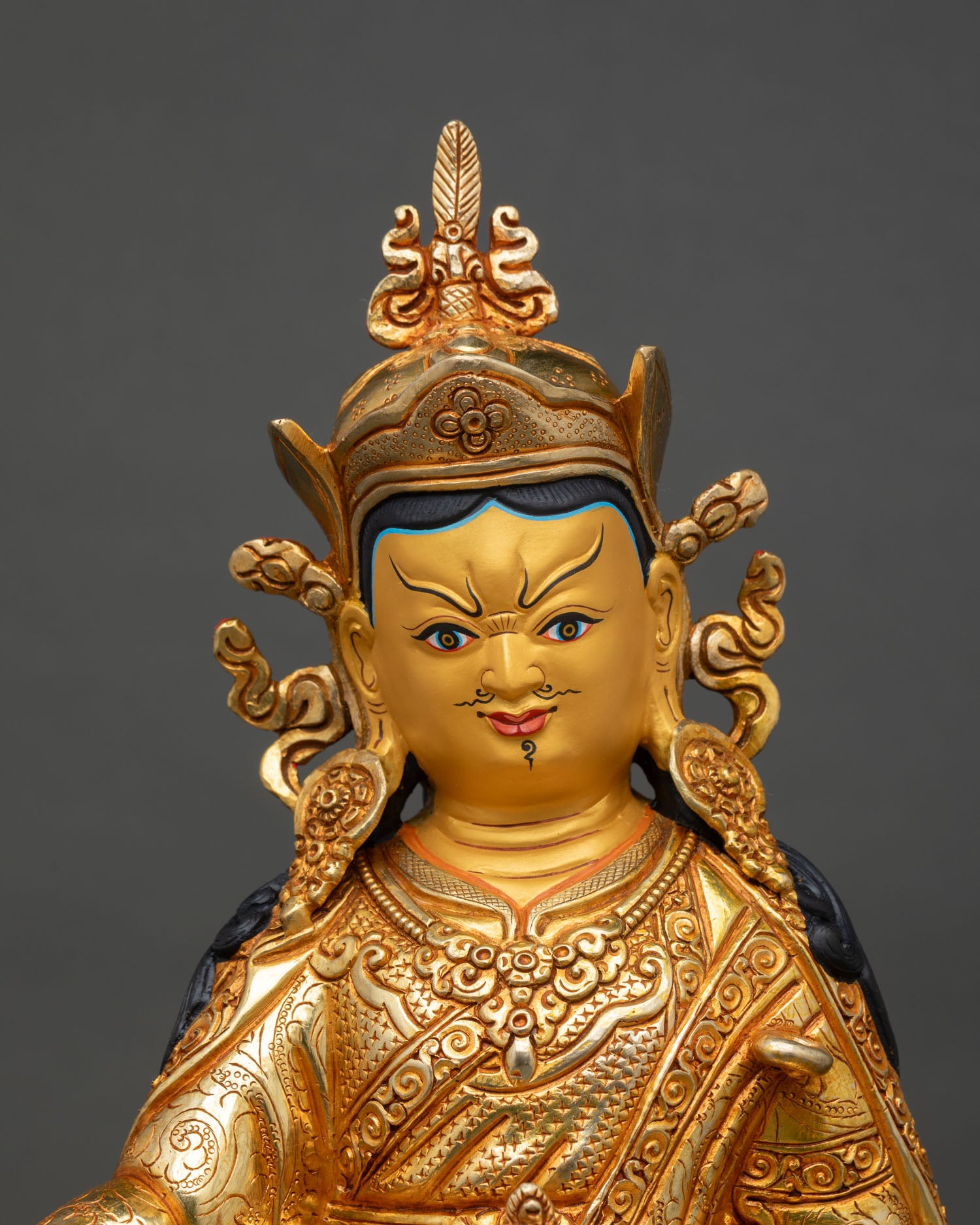 Close up view of Guru Rinpoche statue serene gold painted face with detailed Newari craftsmanship and sacred Himalayan artistry