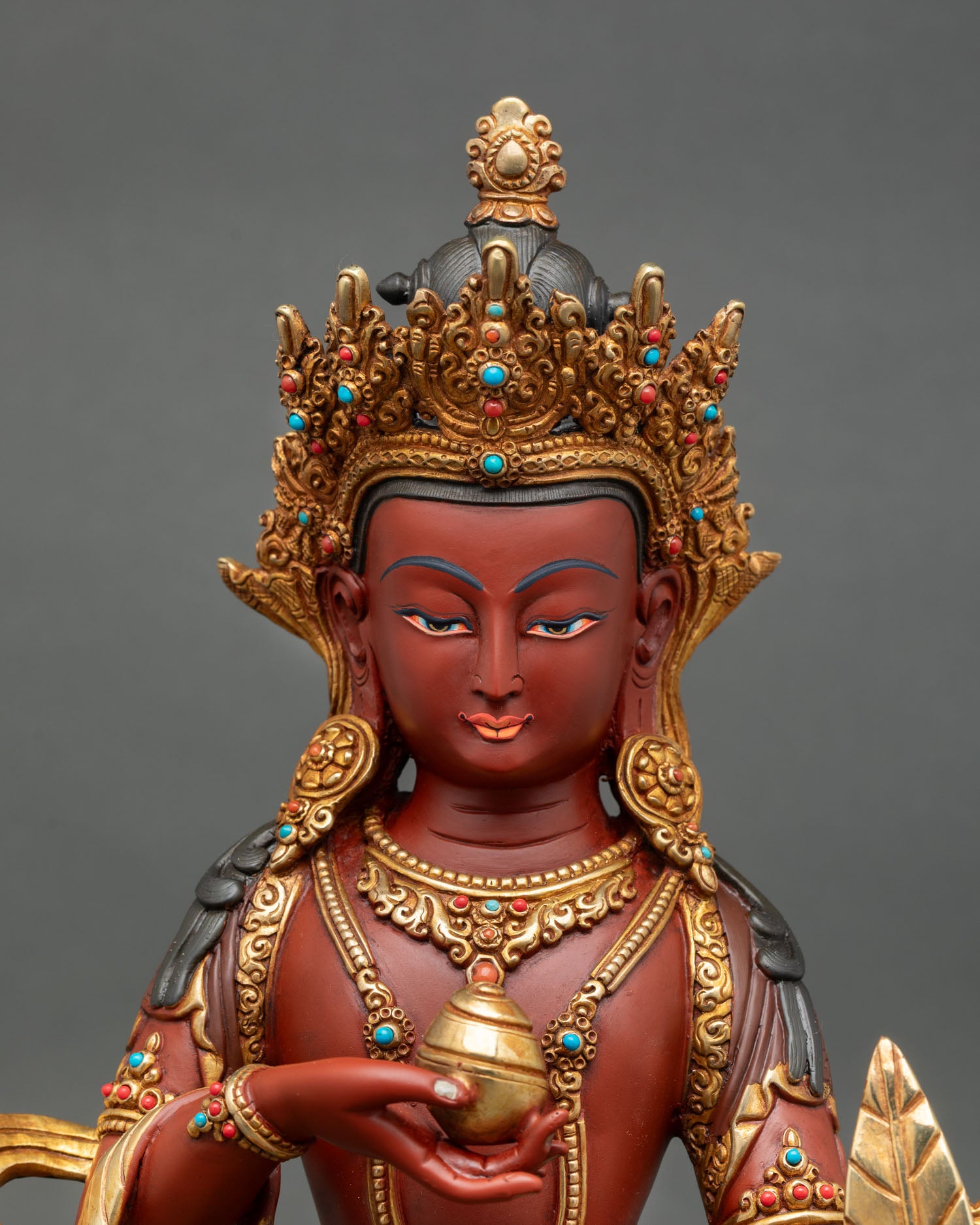 Close-up view of Ksitigarbha statue face detail, turquoise and coral stone inlay, fine Himalayan metal craftsmanship