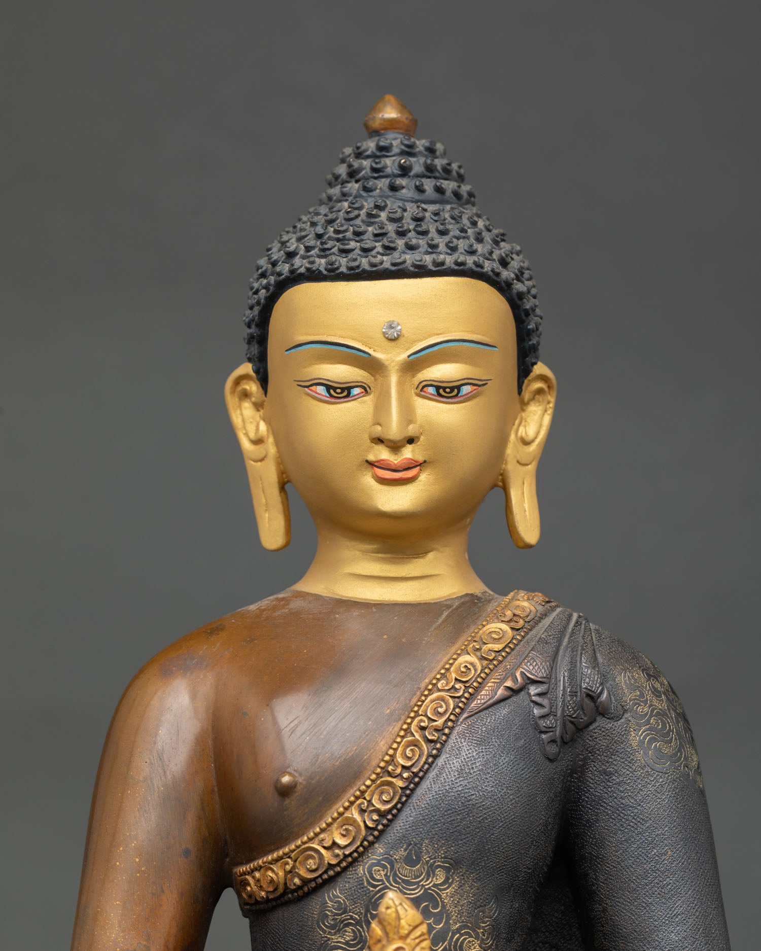 Close up view of Medicine Buddha statue finely gold painted face with serene expression detailed Newari craftsmanship