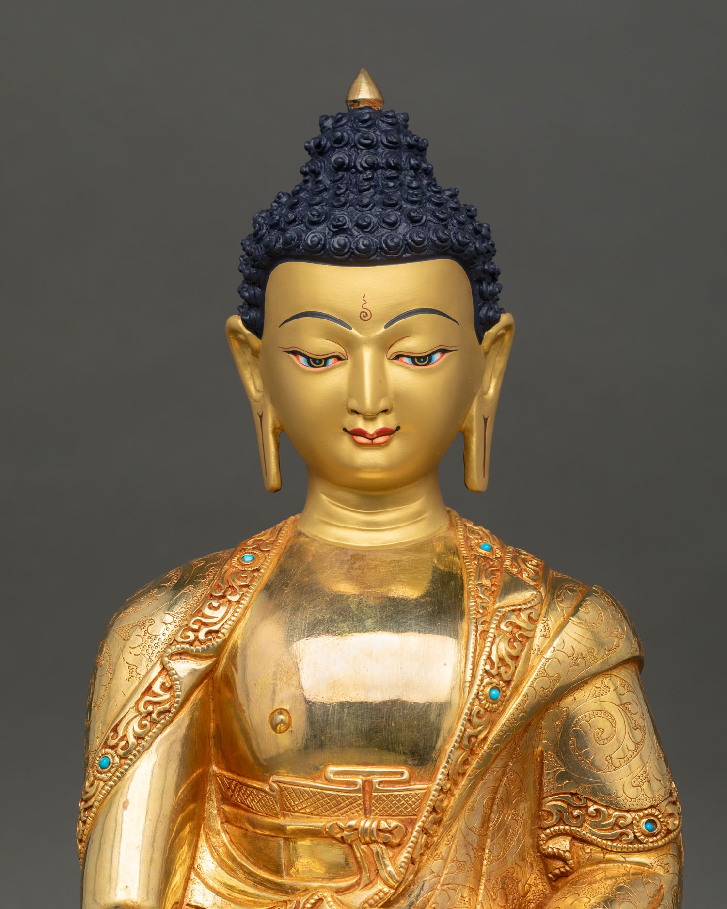 Close-up view of Shakyamuni Buddha's face showing a gold-painted, serene expression symbolizing enlightenment and inner peace, with detailed Himalayan craftsmanship