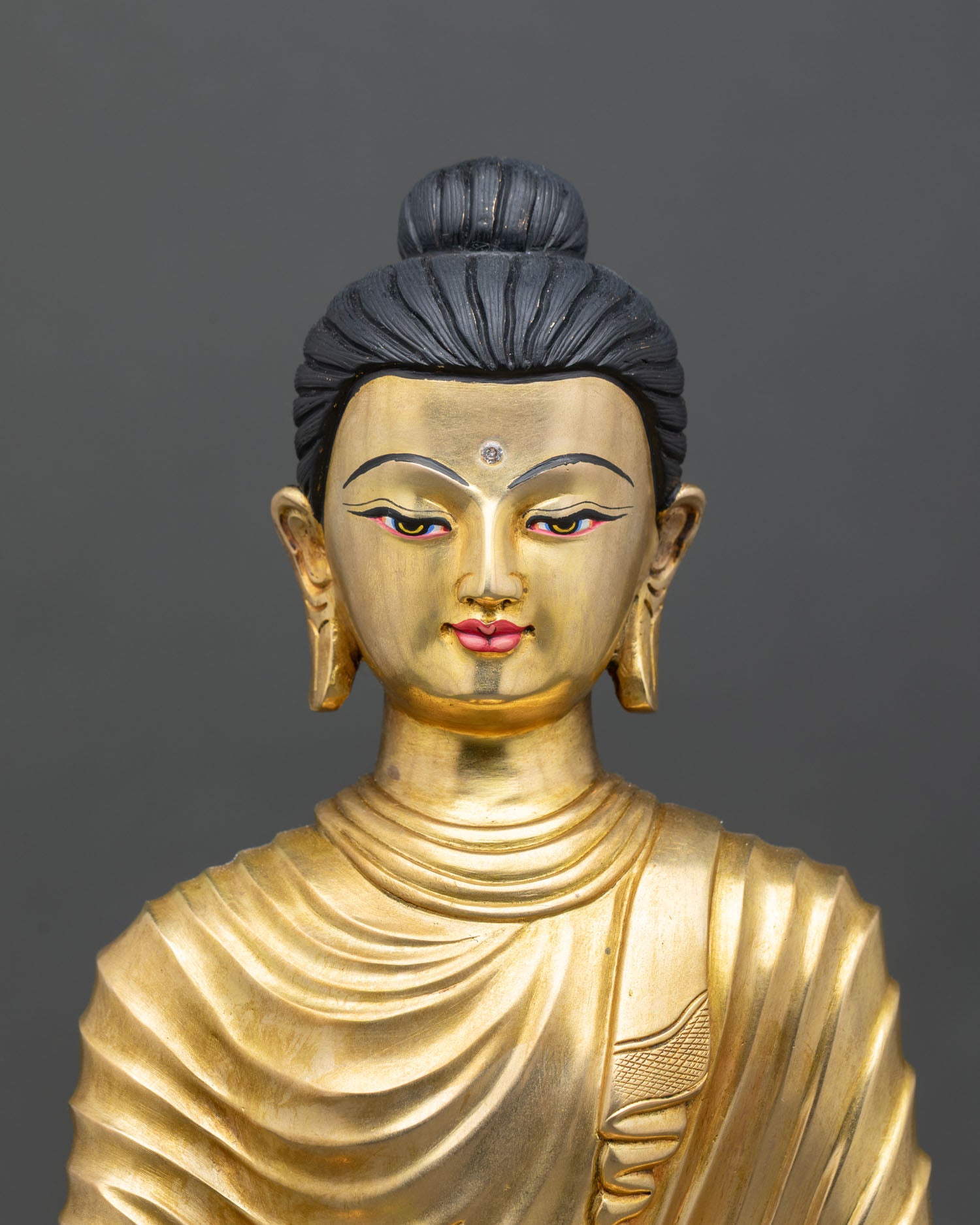 Close up view of Shakyamuni Buddha statue showing gold painted face serene expression, Himalayan craftsmanship
