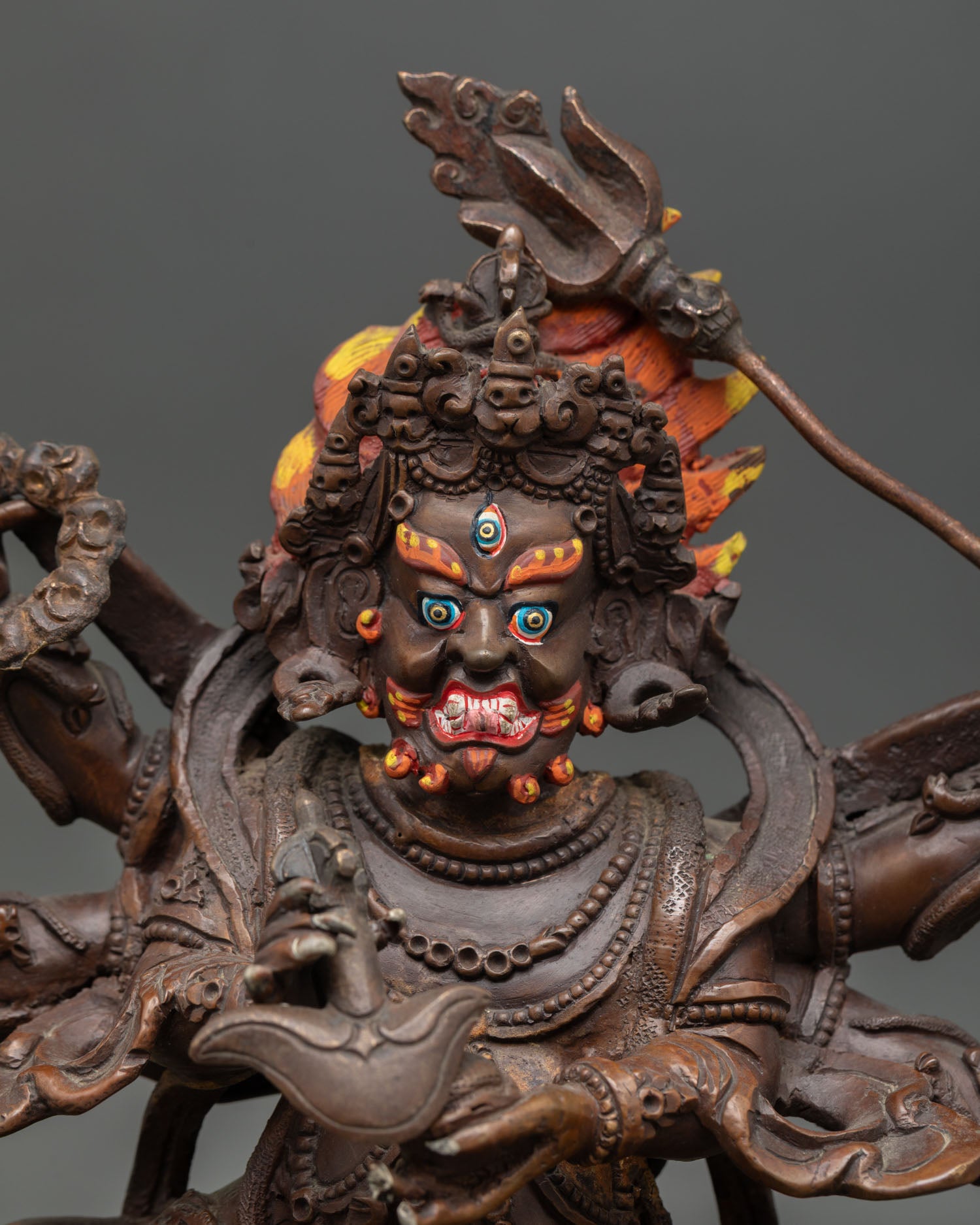 Close up view of Six-Armed Mahakala face with three eyes, gold painted crown and flaming hair detail, Himalayan Buddhist wrathful protector statue by Nepalese artisan.