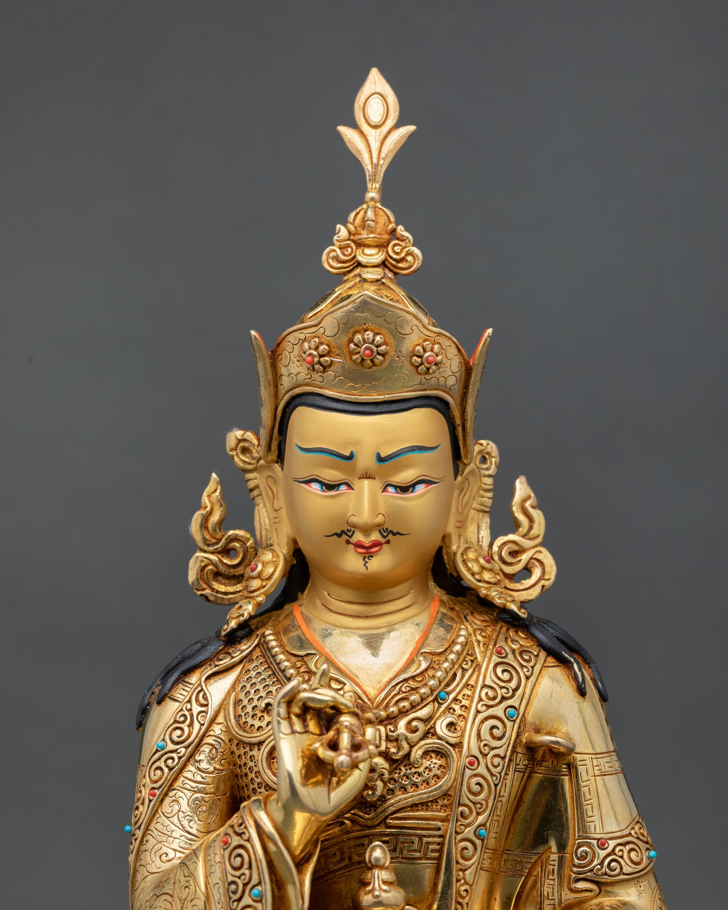 Close up view of Tsokye Dorje statue showing detailed gold painted face with turquoise and coral stone inlays and sacred Buddhist symbolism