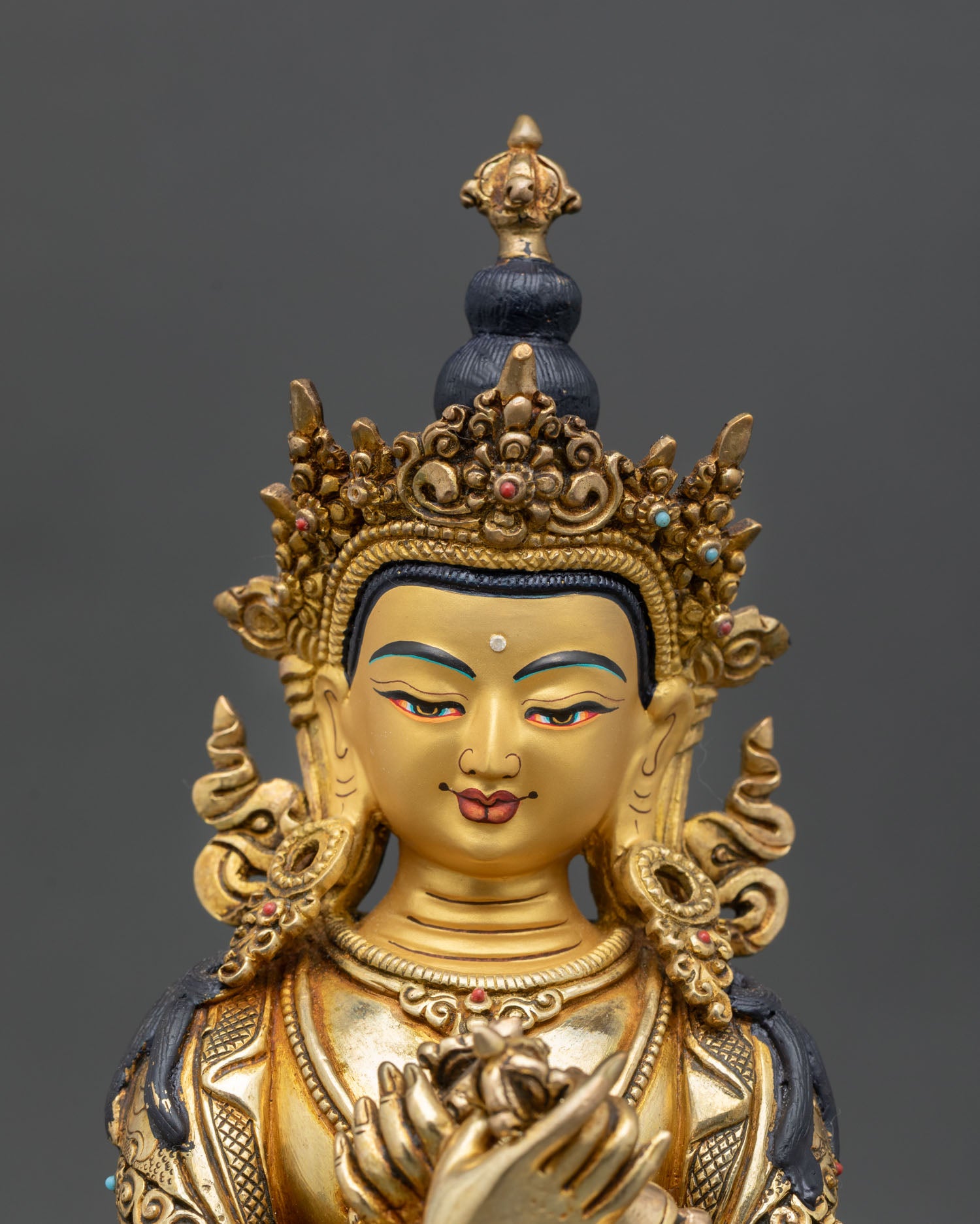 Close up view of Vajradhara Buddhist deity showing gold painted facial details serene expression and intricate Himalayan artisan craftsmanship