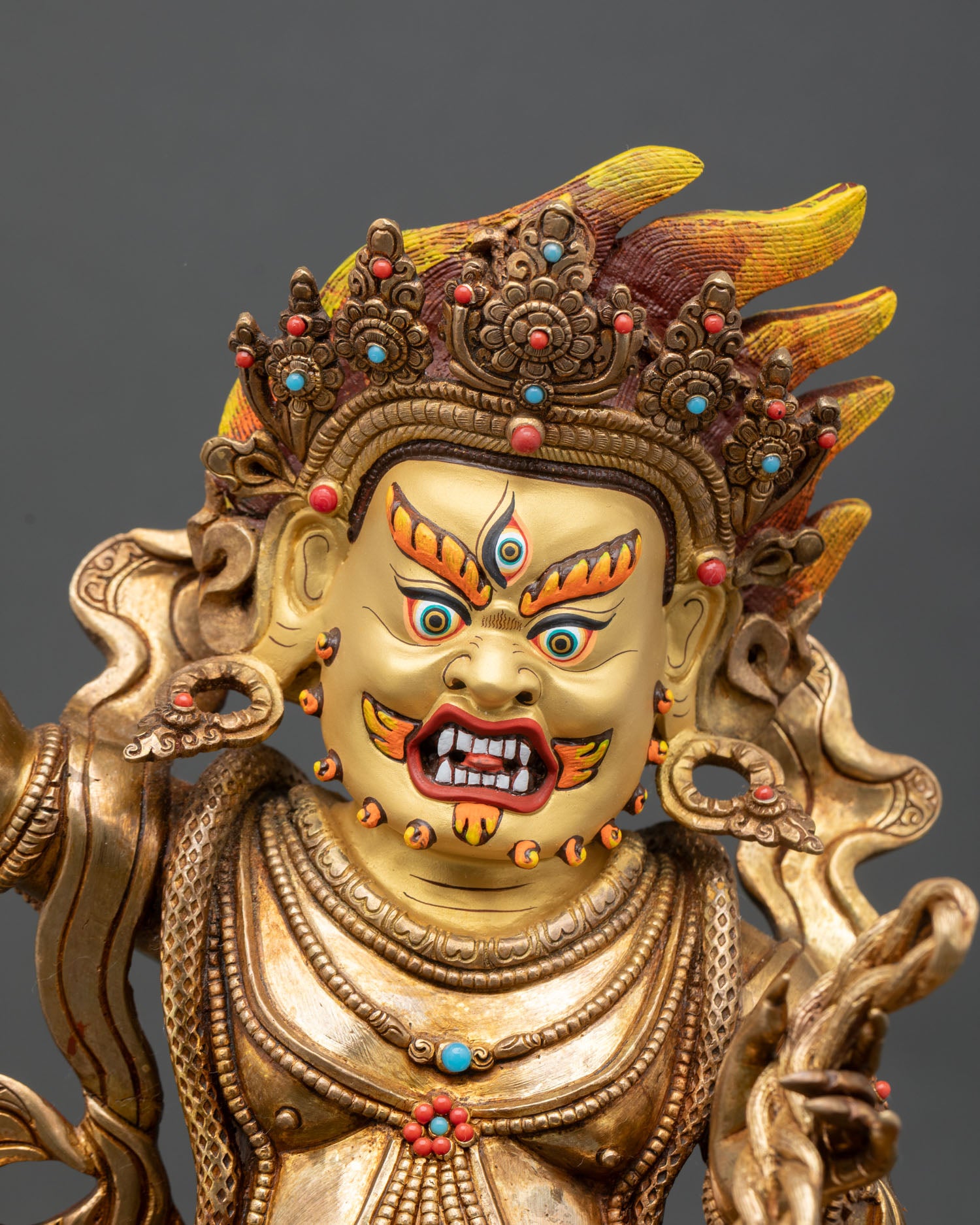 Close up view of Vajrapani statue three eyed gaze gold painted face semi precious stone detailing