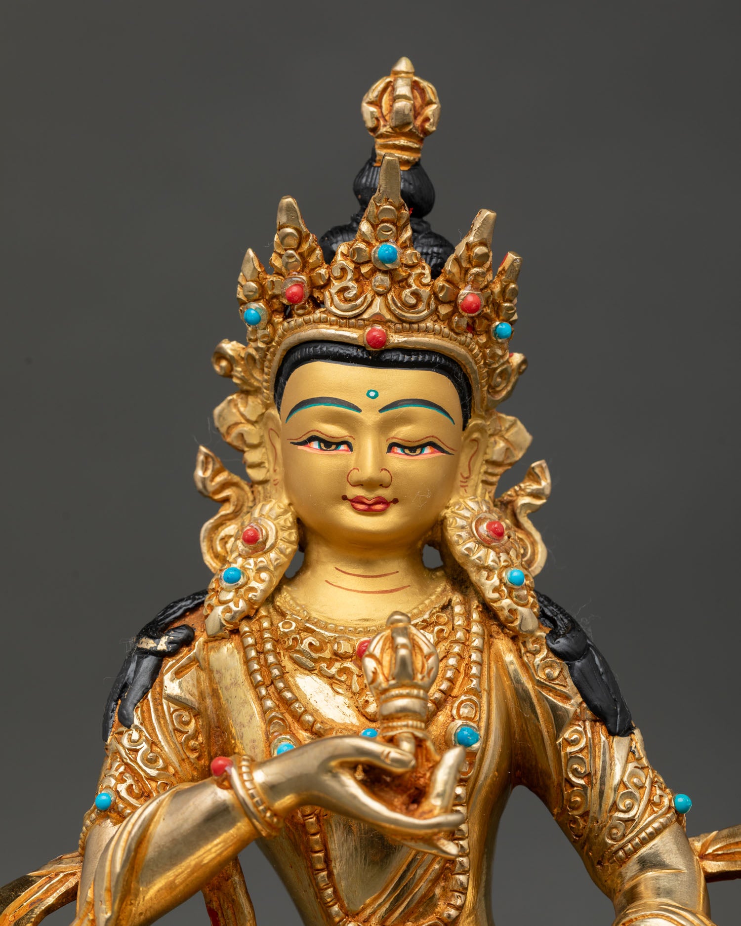 Close up view of Vajrasattva Buddha statue showing gold painted face, five jeweled crown, and intricate ornaments.