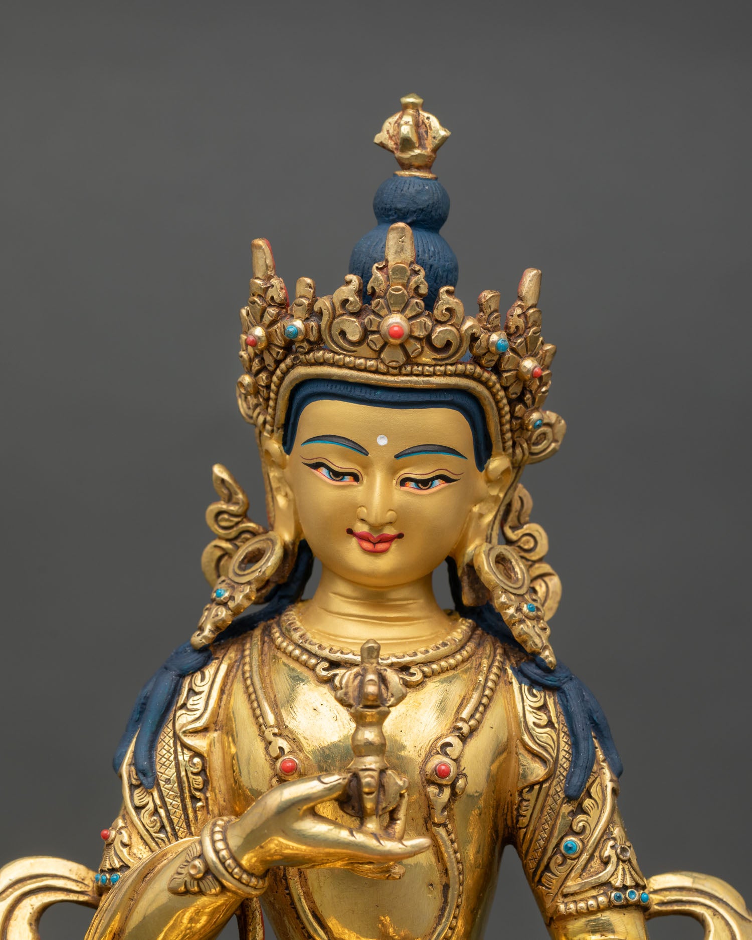 Close-up view of the Vajrasattva statue showing a gold-painted face, and semi-precious stone, with detailed sacred ornaments